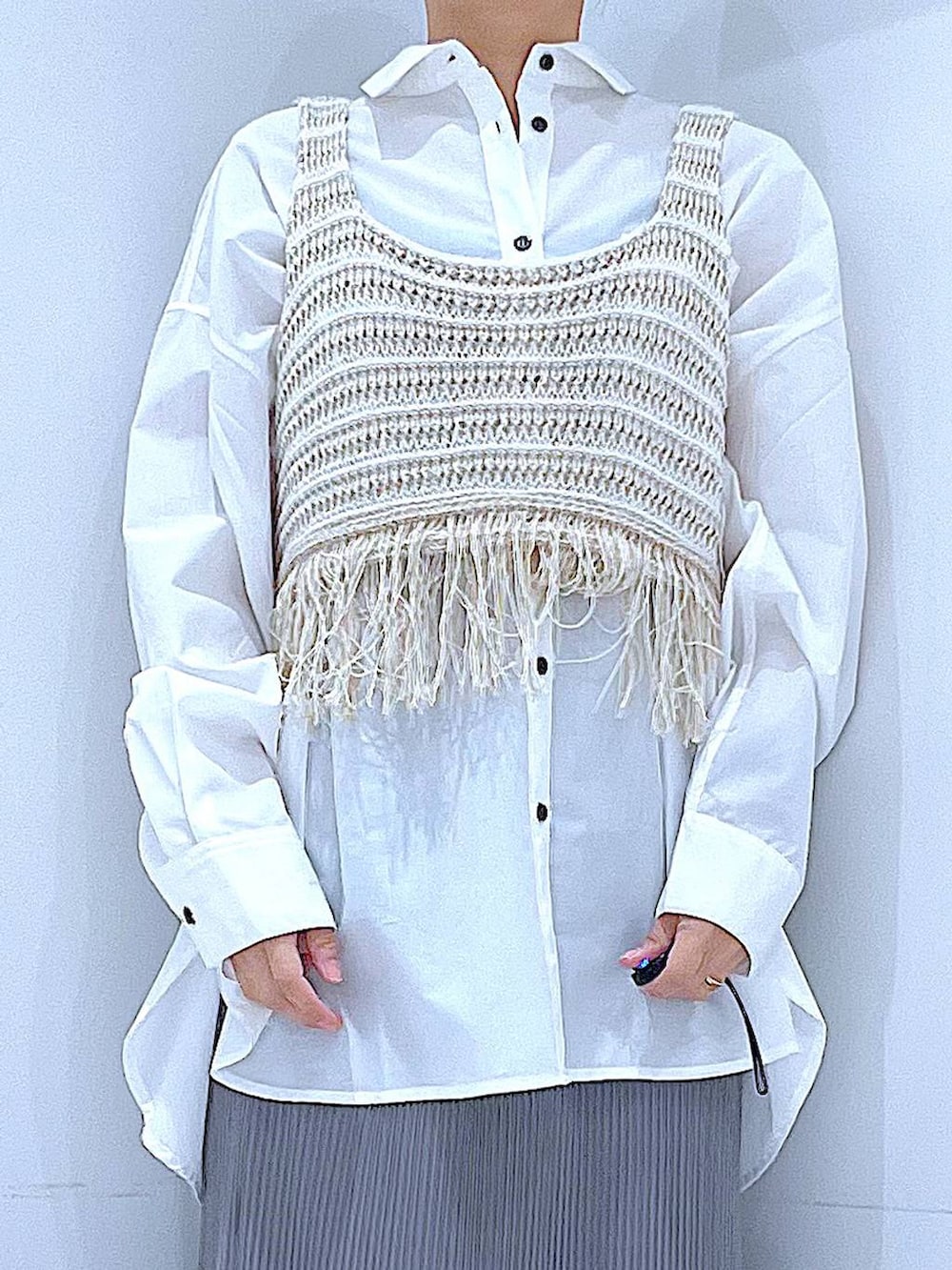 ブラック系のショルダーバッグ、ベージュ系のベスト、グレー系のスカートを着用したレディースの春コーディネートの7枚目の写真