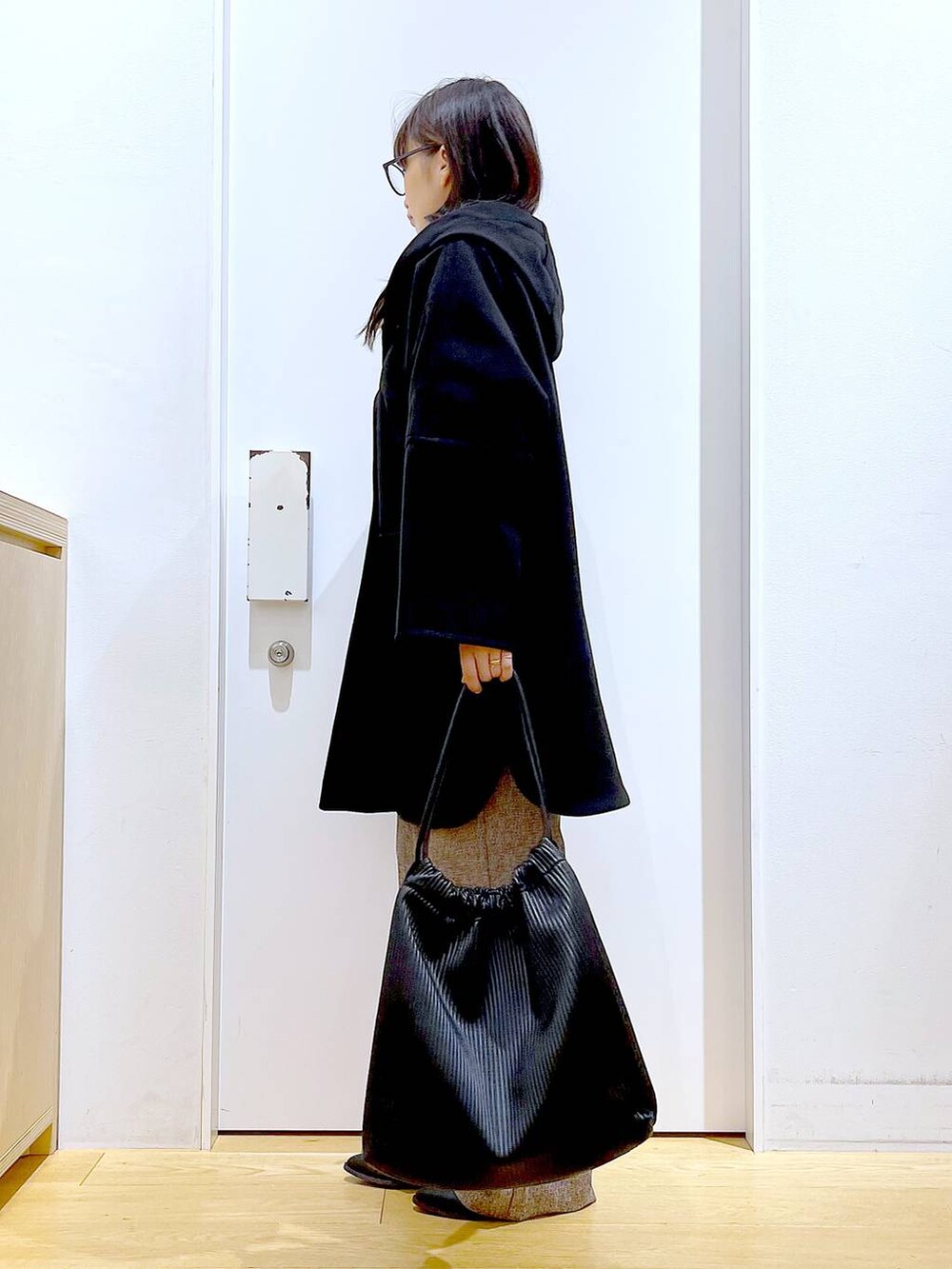 ブラック系のその他アウター、ブラック系のブーツ、ブラック系のトートバッグを着用したレディースの冬コーディネートの3枚目の写真