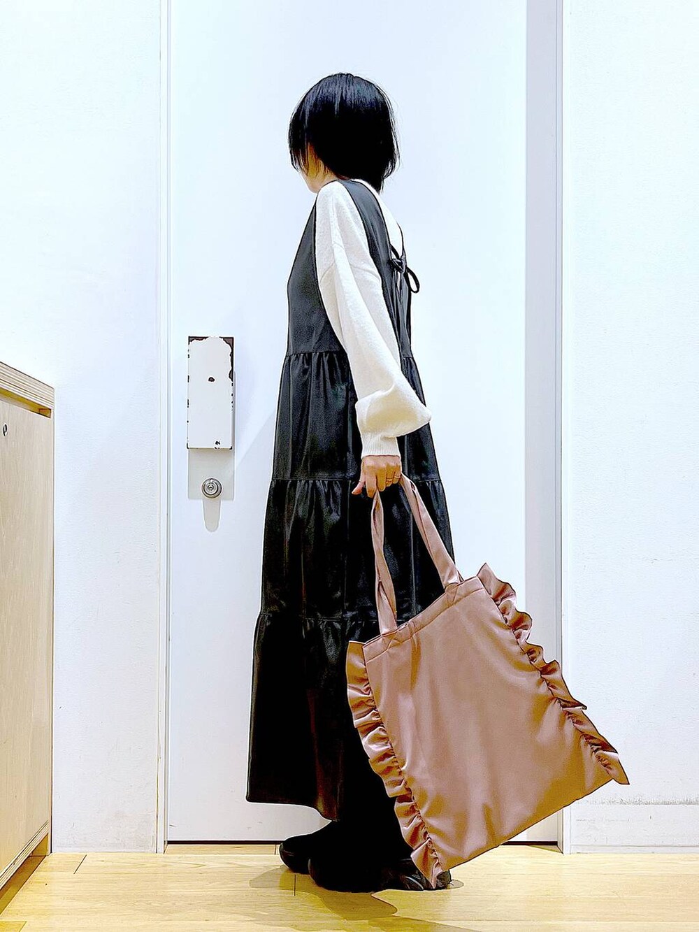 ブラック系のブーツ、ブラック系のワンピース、ピンク系のトートバッグを着用したレディースの冬コーディネートの3枚目の写真