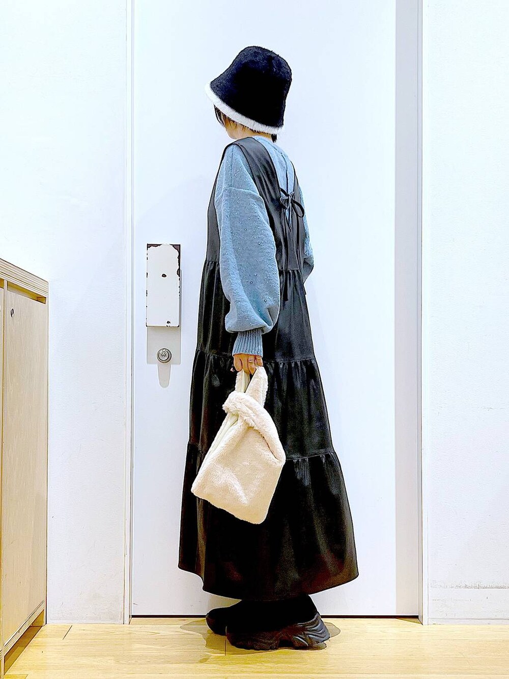 ホワイト系のショルダーバッグ、ブラック系のブーツ、ブラック系のワンピースを着用したレディースの冬コーディネートの3枚目の写真