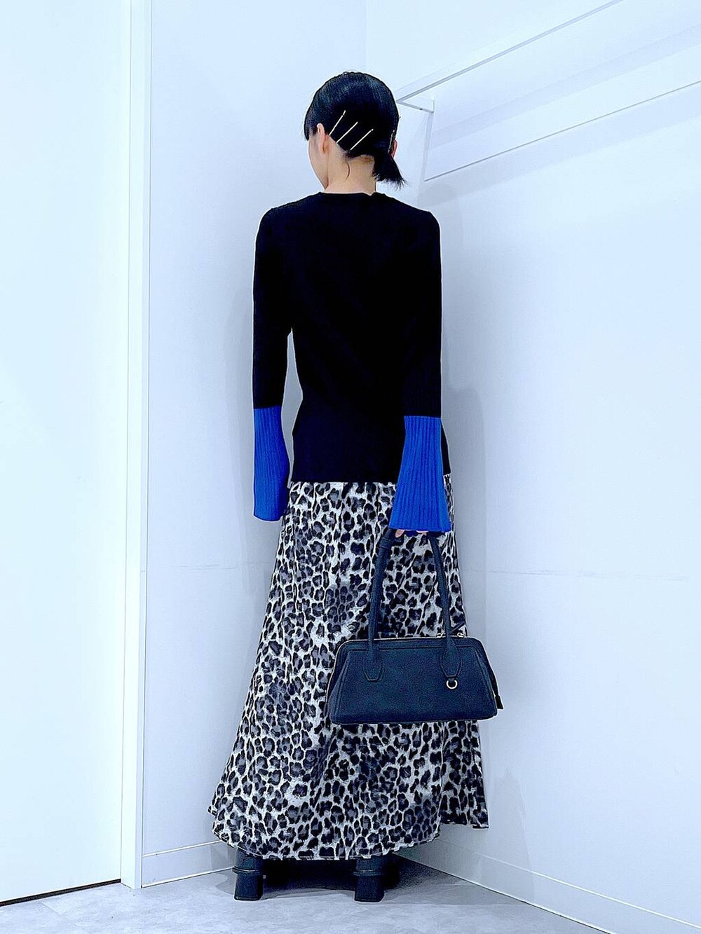 ブラック系のニット/セーター、ブラック系のブーツ、グレー系のスカートを着用したレディースの秋コーディネートの5枚目の写真