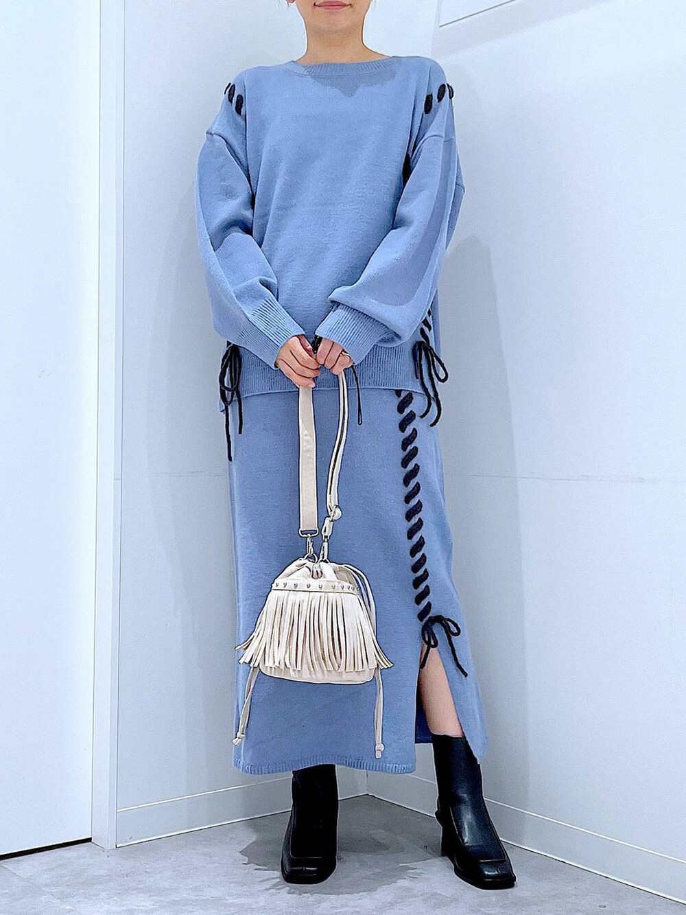 ブルー系のニット/セーター、ブルー系のスカート、ブラック系のブーツを着用したレディースの秋コーディネートの6枚目の写真