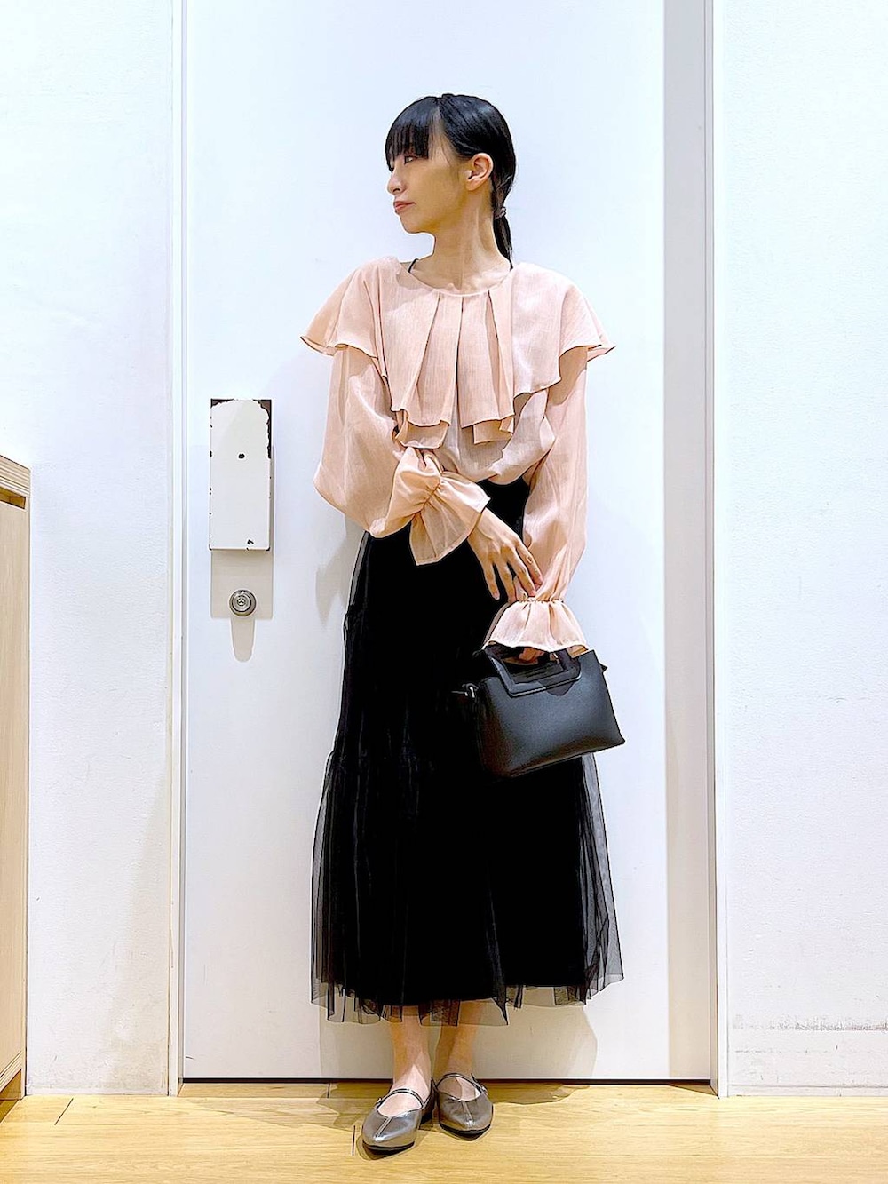 ブラック系のスカート、ブラック系のショルダーバッグ、その他のパンプスを着用したレディースの春コーディネートの2枚目の写真