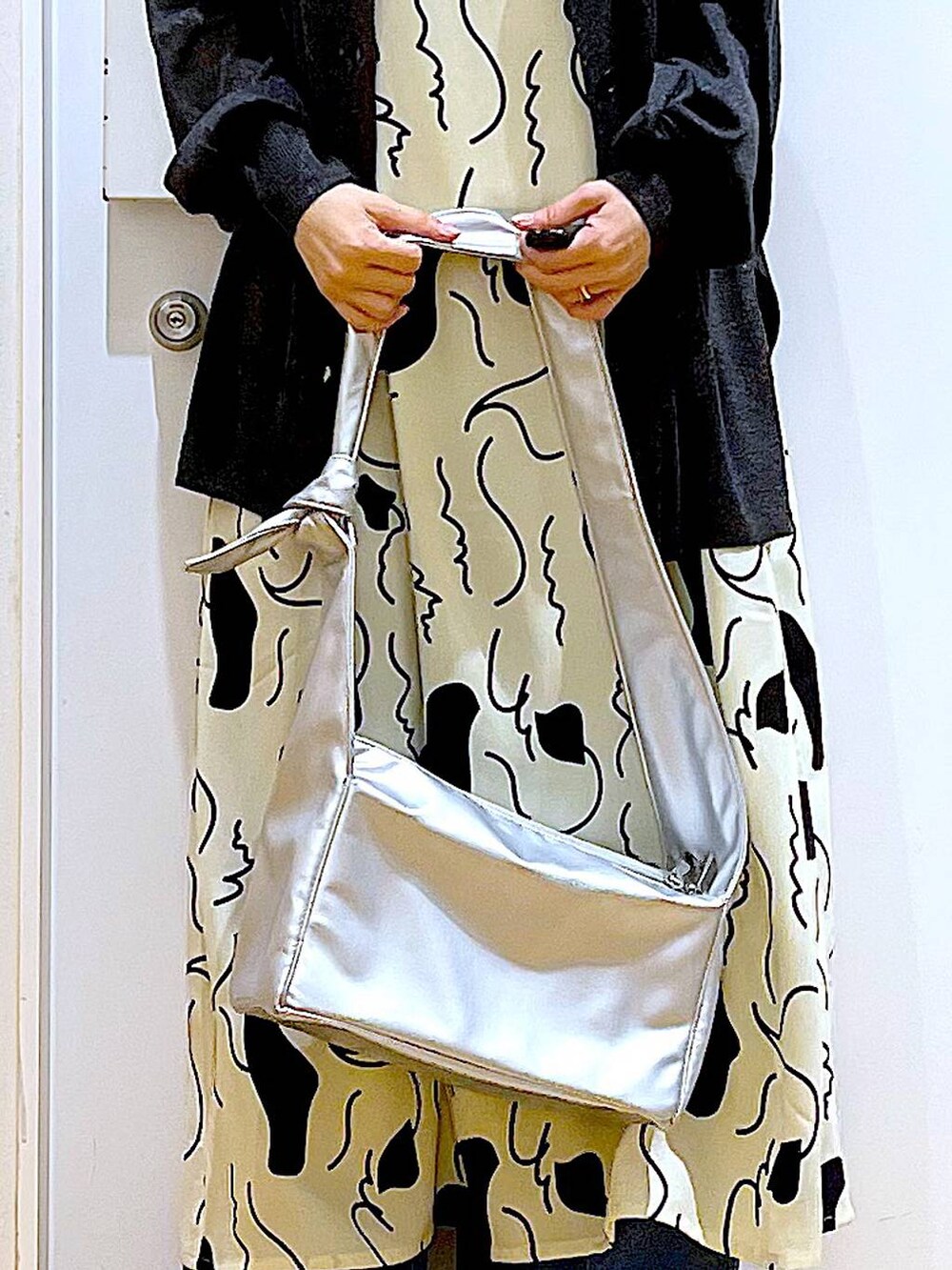 ブルー系のデニムパンツ、ベージュ系のワンピース、シルバー系のショルダーバッグを着用したレディースの春コーディネートの9枚目の写真