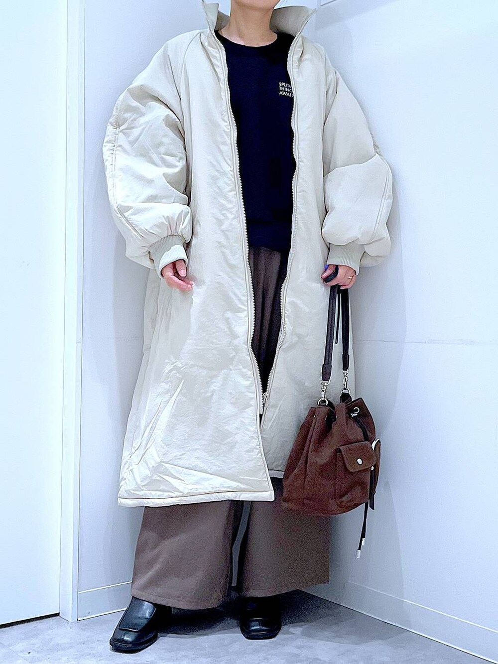 ホワイト系のブルゾン、ブラウン系のショルダーバッグ、ブラック系のブーツを着用したレディースの冬コーディネートの6枚目の写真