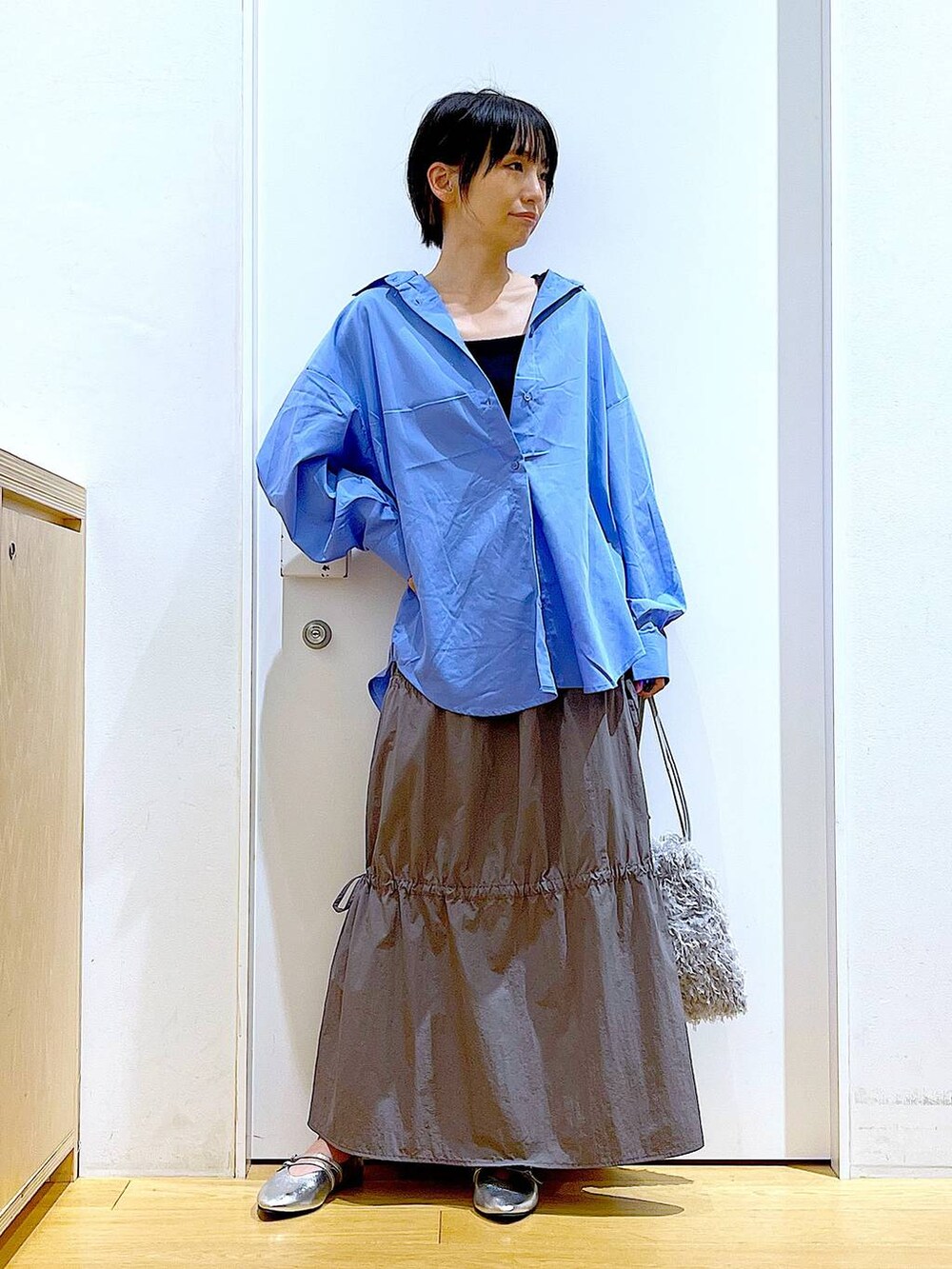 グレー系のショルダーバッグ、シルバー系のパンプス、グレー系のスカートを着用したレディースの秋コーディネートの2枚目の写真