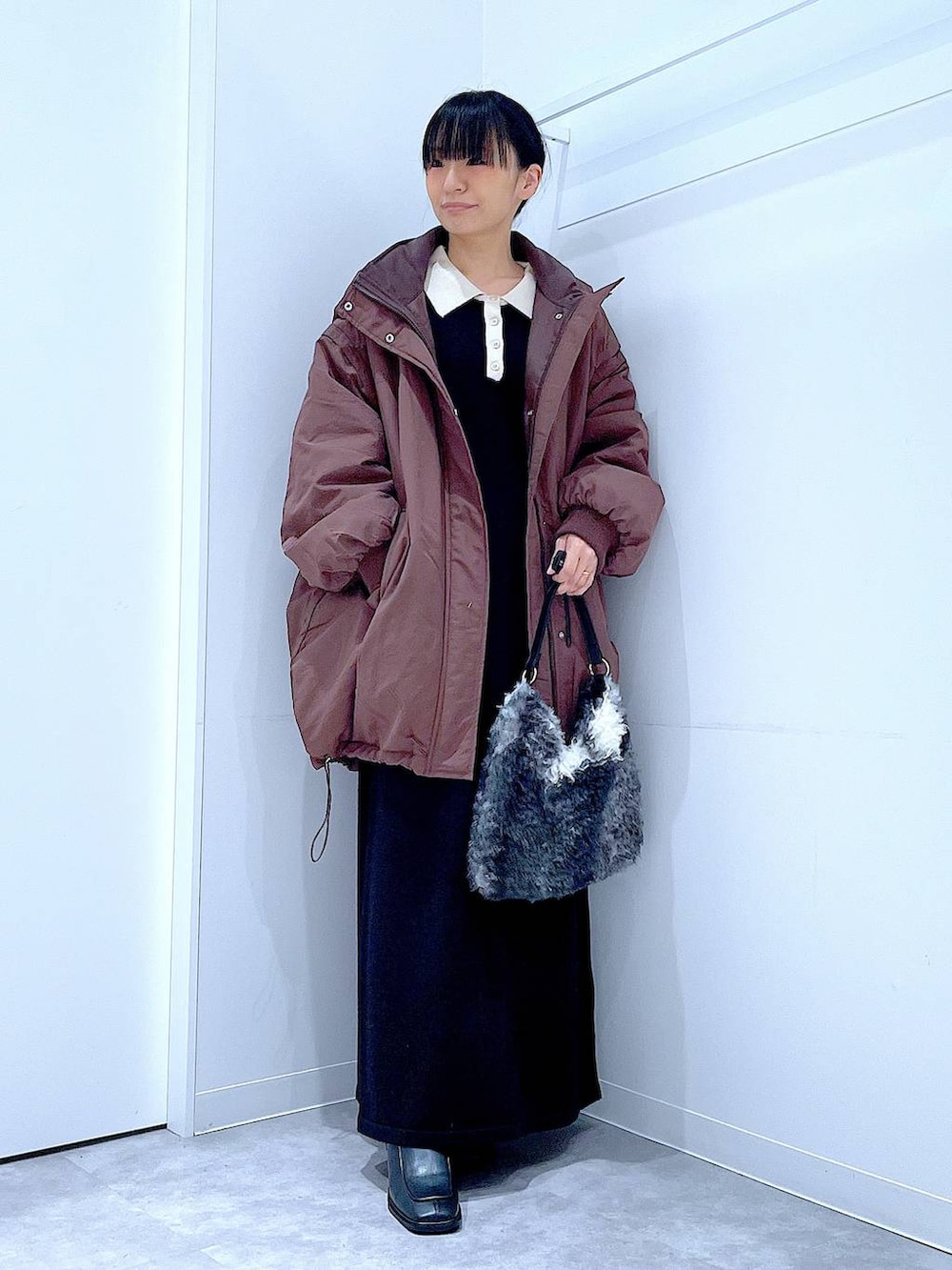 ブラウン系のブルゾン、ブラック系のブーツ、ブラック系のショルダーバッグを着用したレディースの冬コーディネートの2枚目の写真