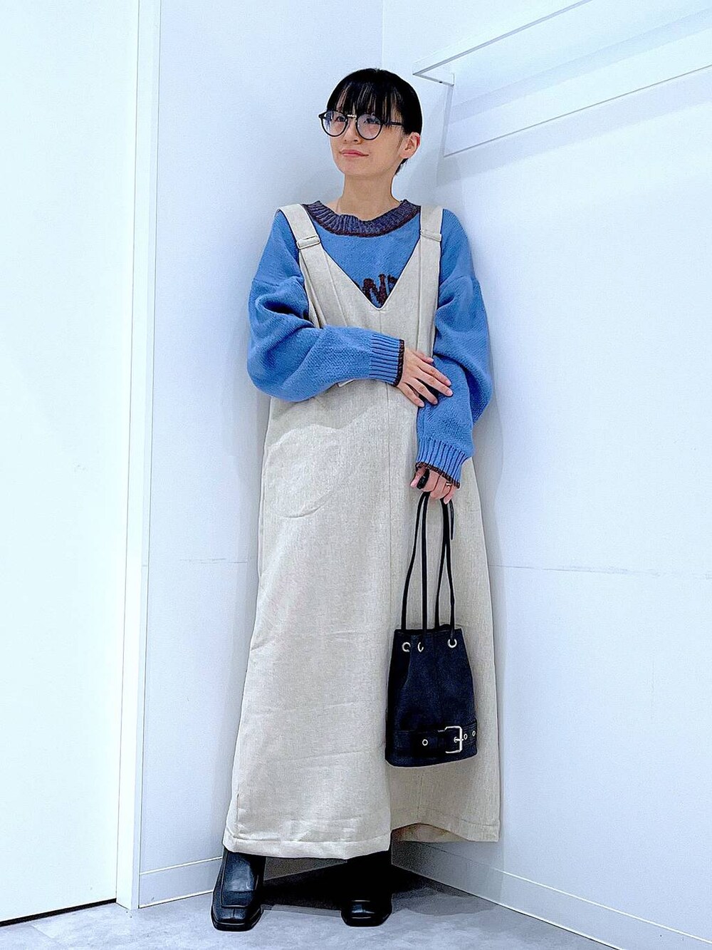 ブラック系のブーツ、ブラック系のハンドバッグ、ブルー系のニット/セーターを着用したレディースの秋コーディネートの2枚目の写真