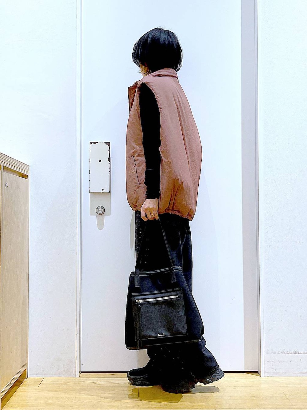 ブラウン系のベスト、ブラック系のトートバッグ、ブラック系のTシャツ/カットソーを着用したレディースの秋コーディネートの3枚目の写真