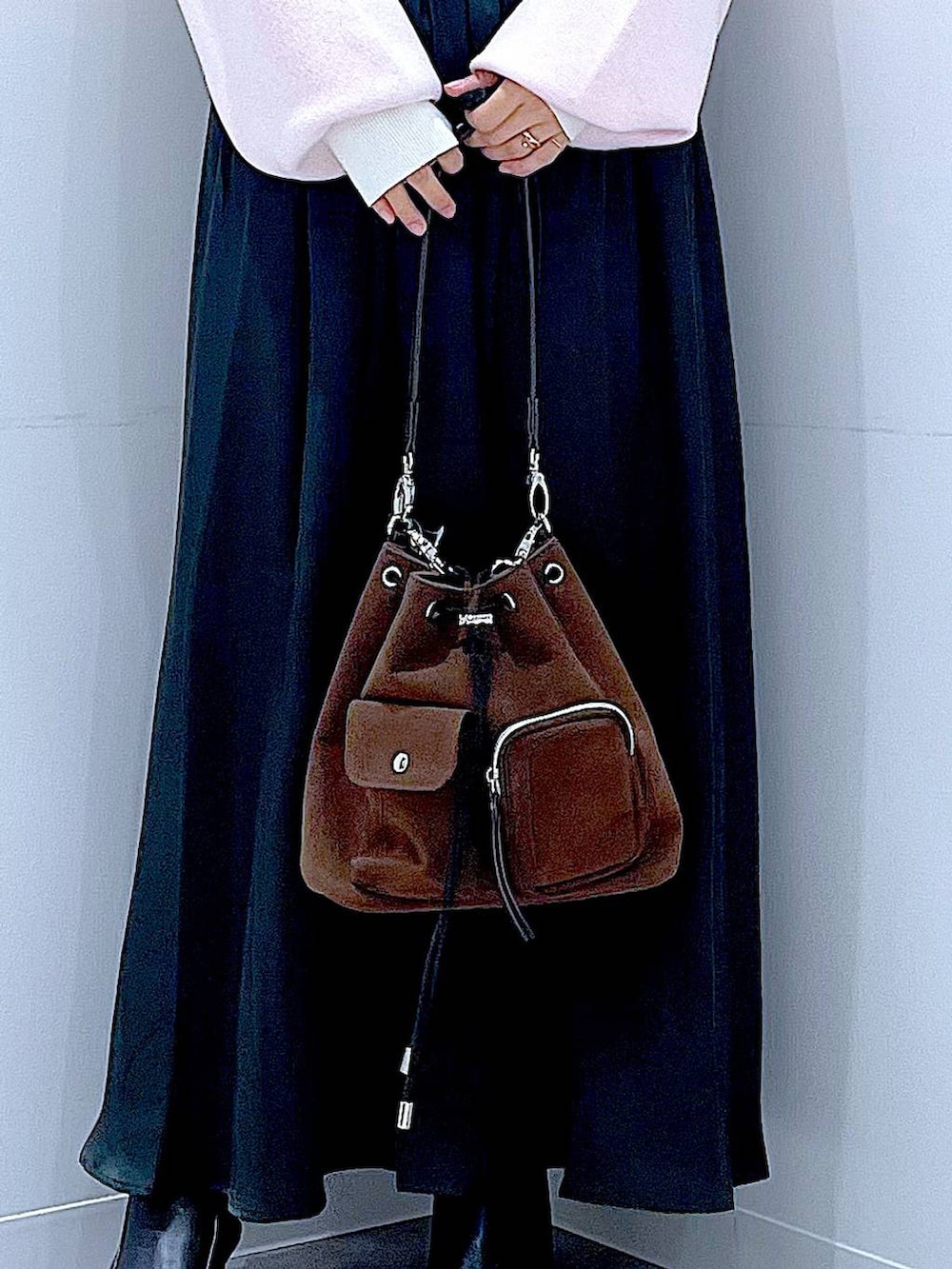 ブラウン系のショルダーバッグ、ブラック系のブーツ、ベージュ系のニット/セーターを着用したレディースの冬コーディネートの9枚目の写真