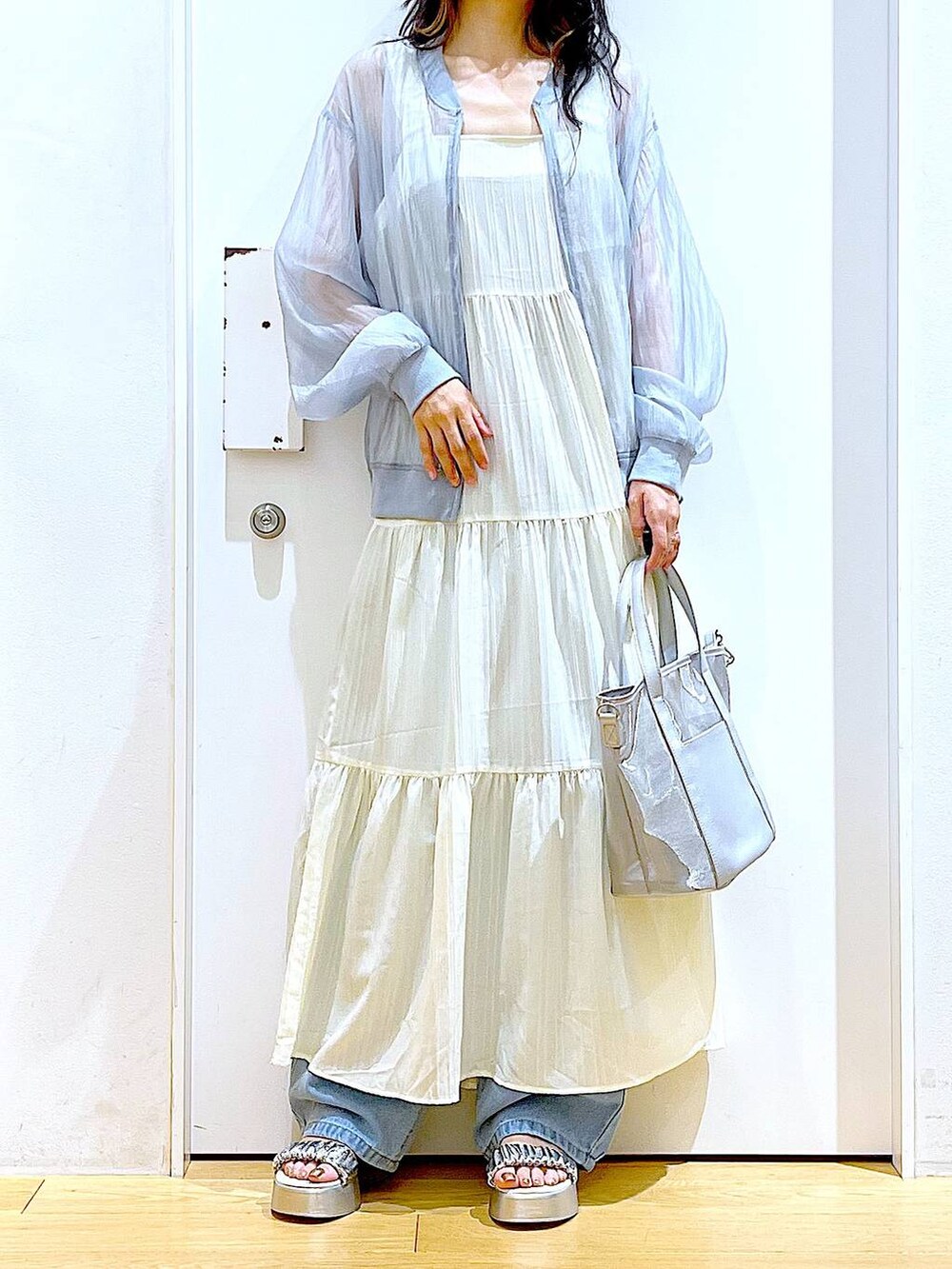 ブルー系のデニムパンツ、シルバー系のトートバッグ、シルバー系のサンダルを着用したレディースの夏コーディネートの6枚目の写真