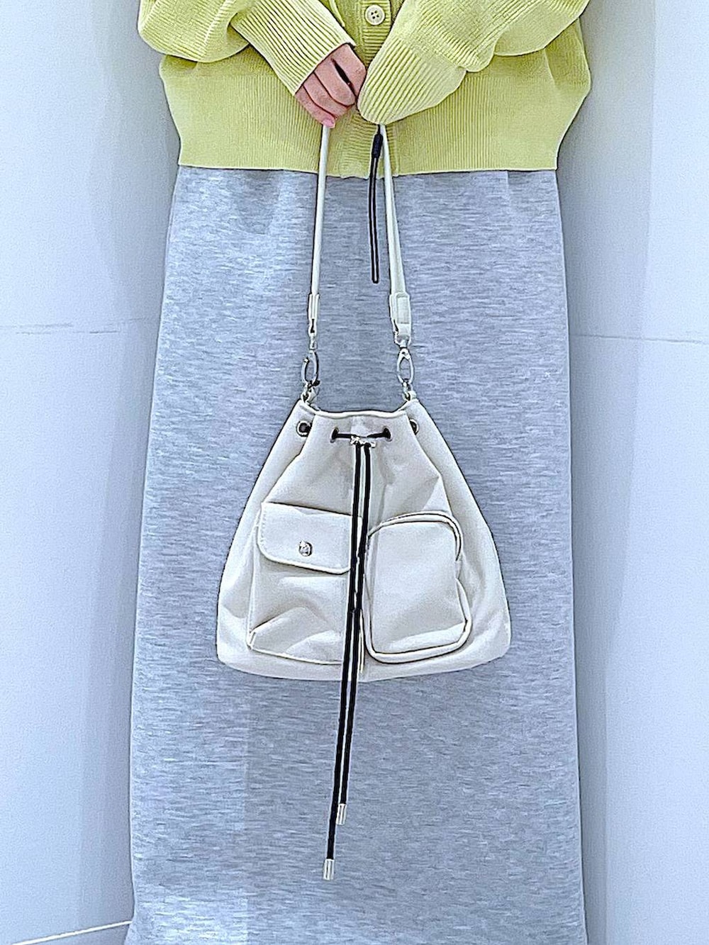 ベージュ系のショルダーバッグ、グレー系のスカート、イエロー系のカーディガン/ボレロを着用したレディースの春コーディネートの9枚目の写真