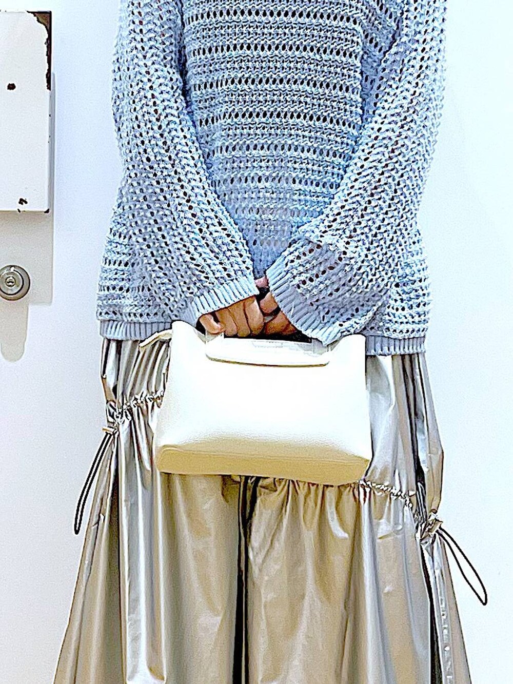 ブルー系のニット/セーター、シルバー系のスカート、ホワイト系のショルダーバッグを着用したレディースの春コーディネートの9枚目の写真