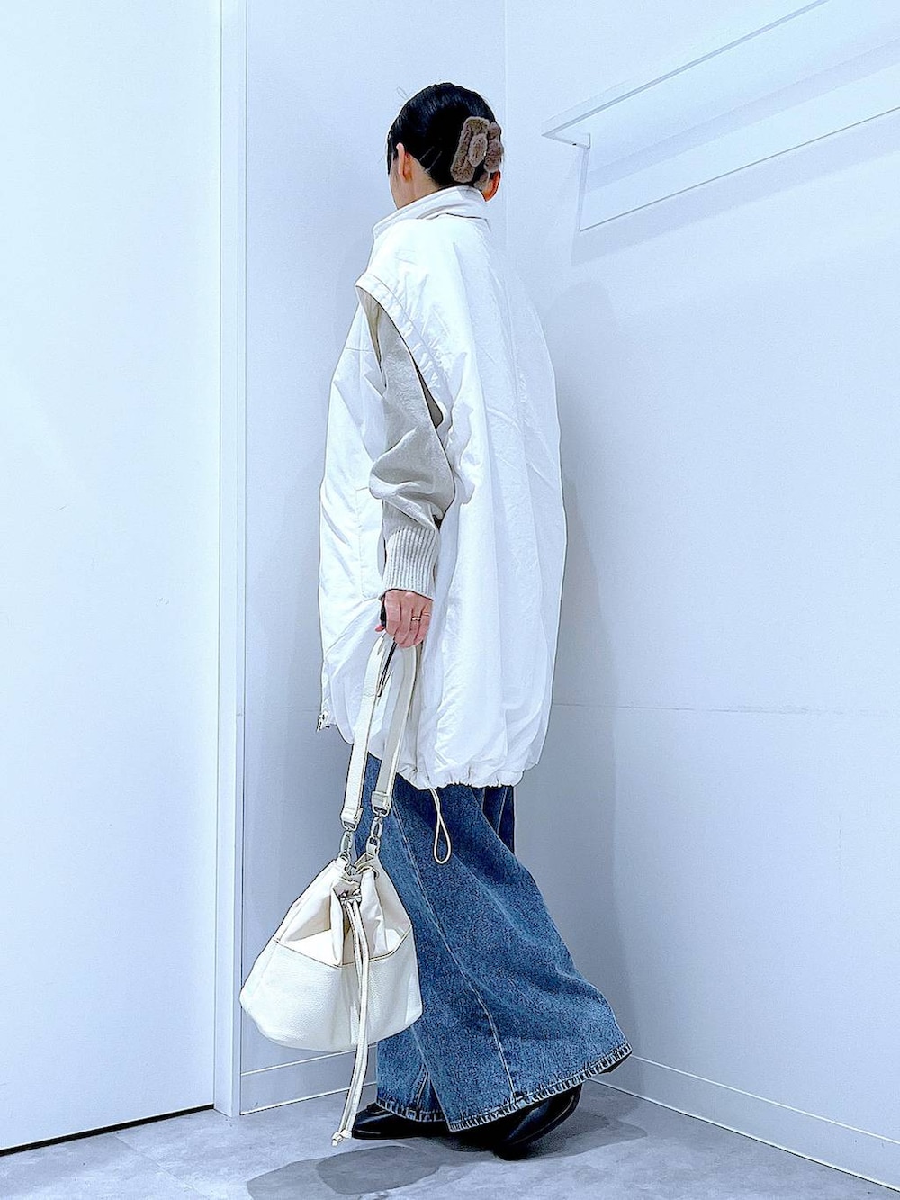 ホワイト系のブルゾン、ブルー系のデニムパンツ、ホワイト系のショルダーバッグを着用したレディースの冬コーディネートの3枚目の写真