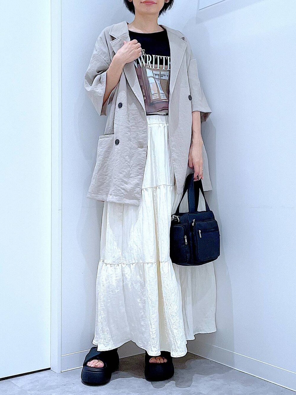 ブラック系のサンダル、ベージュ系のテーラードジャケット、ブラック系のショルダーバッグを着用したレディースの夏コーディネートの6枚目の写真