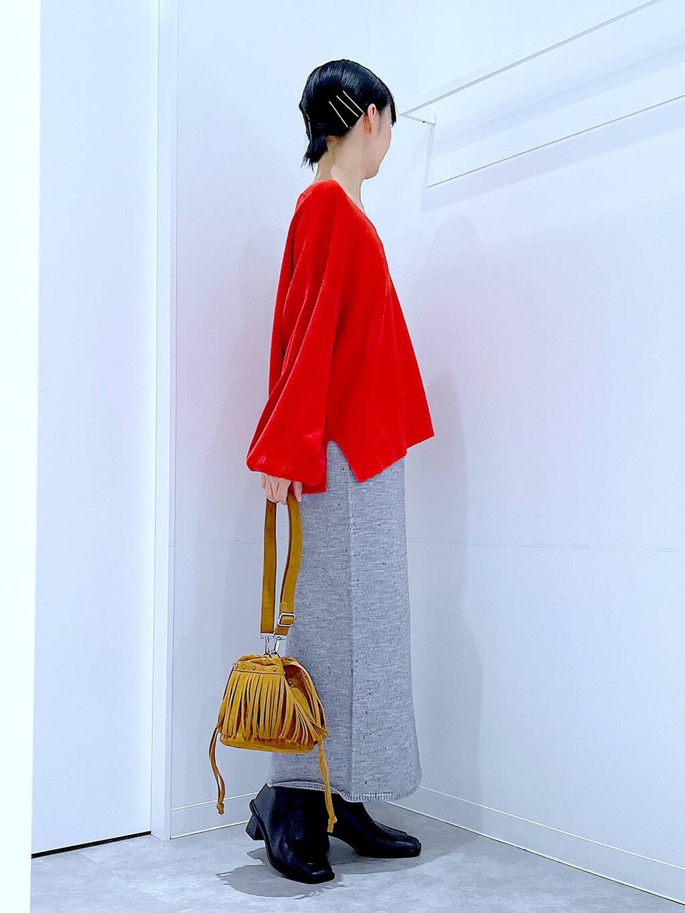 レッド系のニット/セーター、グレー系のスカート、ブラック系のブーツを着用したレディースの秋コーディネートの4枚目の写真