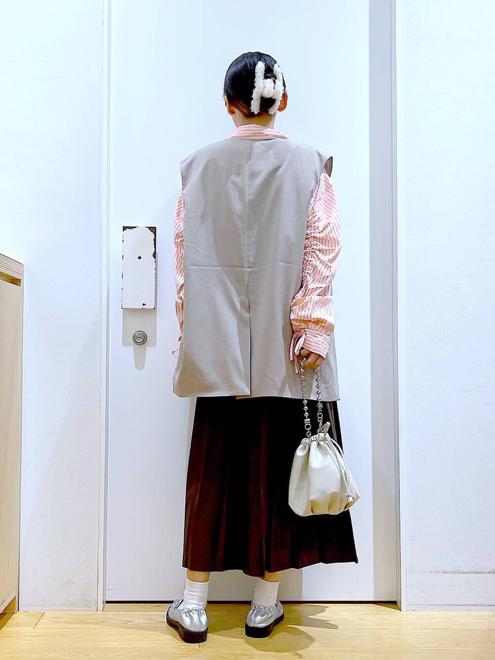 ベージュ系のショルダーバッグ、シルバー系のローファー、ベージュ系のベストを着用したレディースの秋コーディネートの5枚目の写真