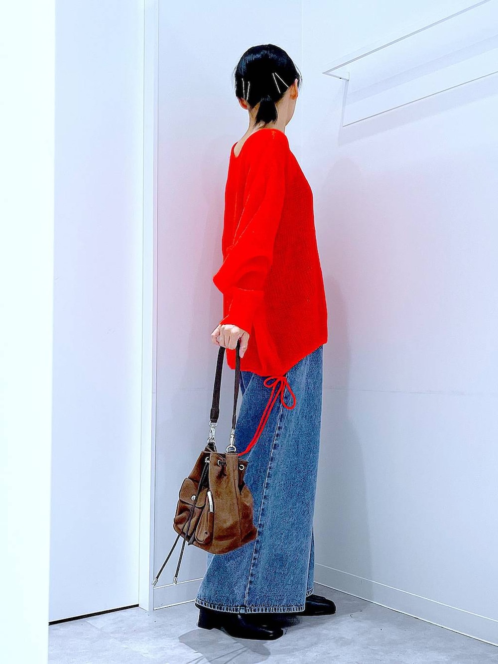 ブラウン系のショルダーバッグ、ブルー系のデニムパンツ、ブラック系のブーツを着用したレディースの秋コーディネートの4枚目の写真