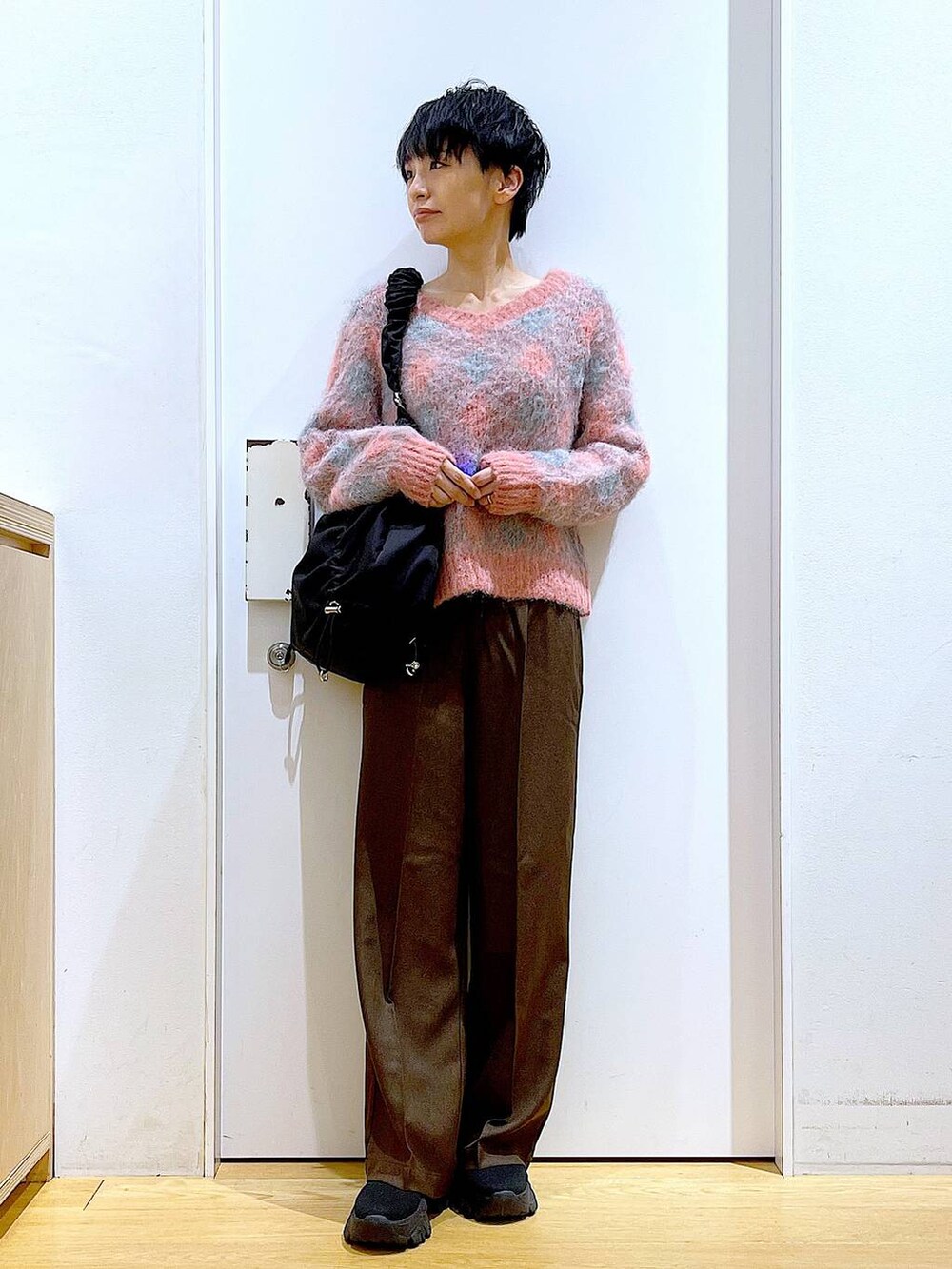 ブラック系のブーツ、ブラック系のショルダーバッグ、ピンク系のニット/セーターを着用したレディースの冬コーディネートの2枚目の写真