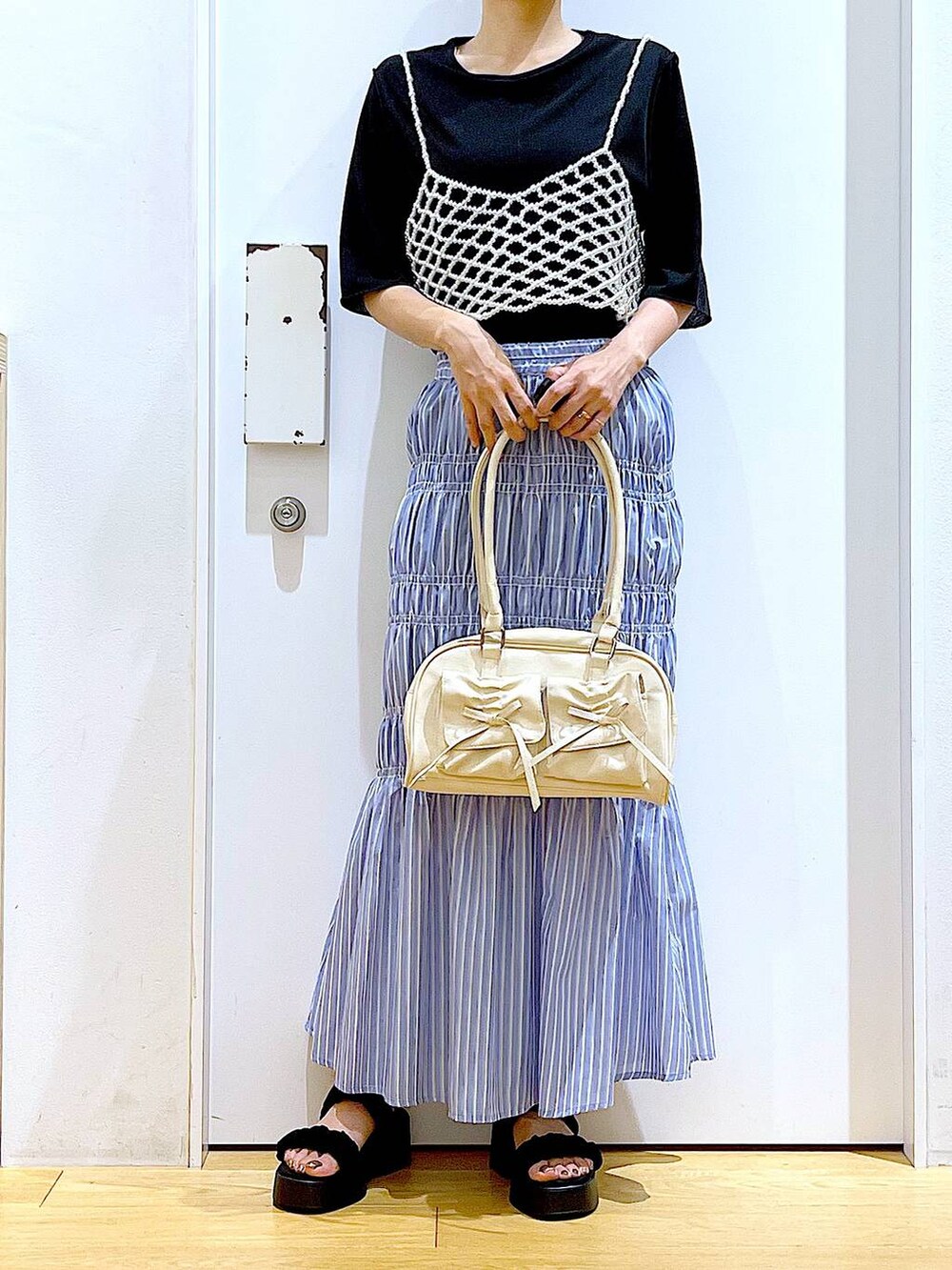 ブラック系のサンダル、ホワイト系のベスト、その他のスカートを着用したレディースの夏コーディネートの6枚目の写真