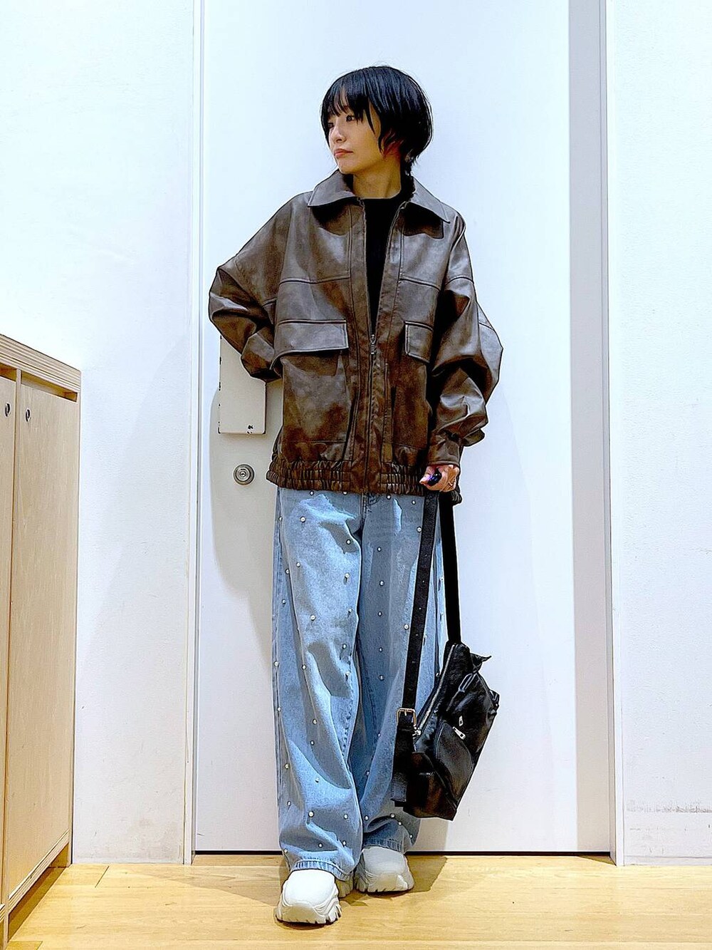 ブラウン系のブルゾン、ベージュ系のブーツ、ブルー系のデニムパンツを着用したレディースの秋コーディネートの2枚目の写真