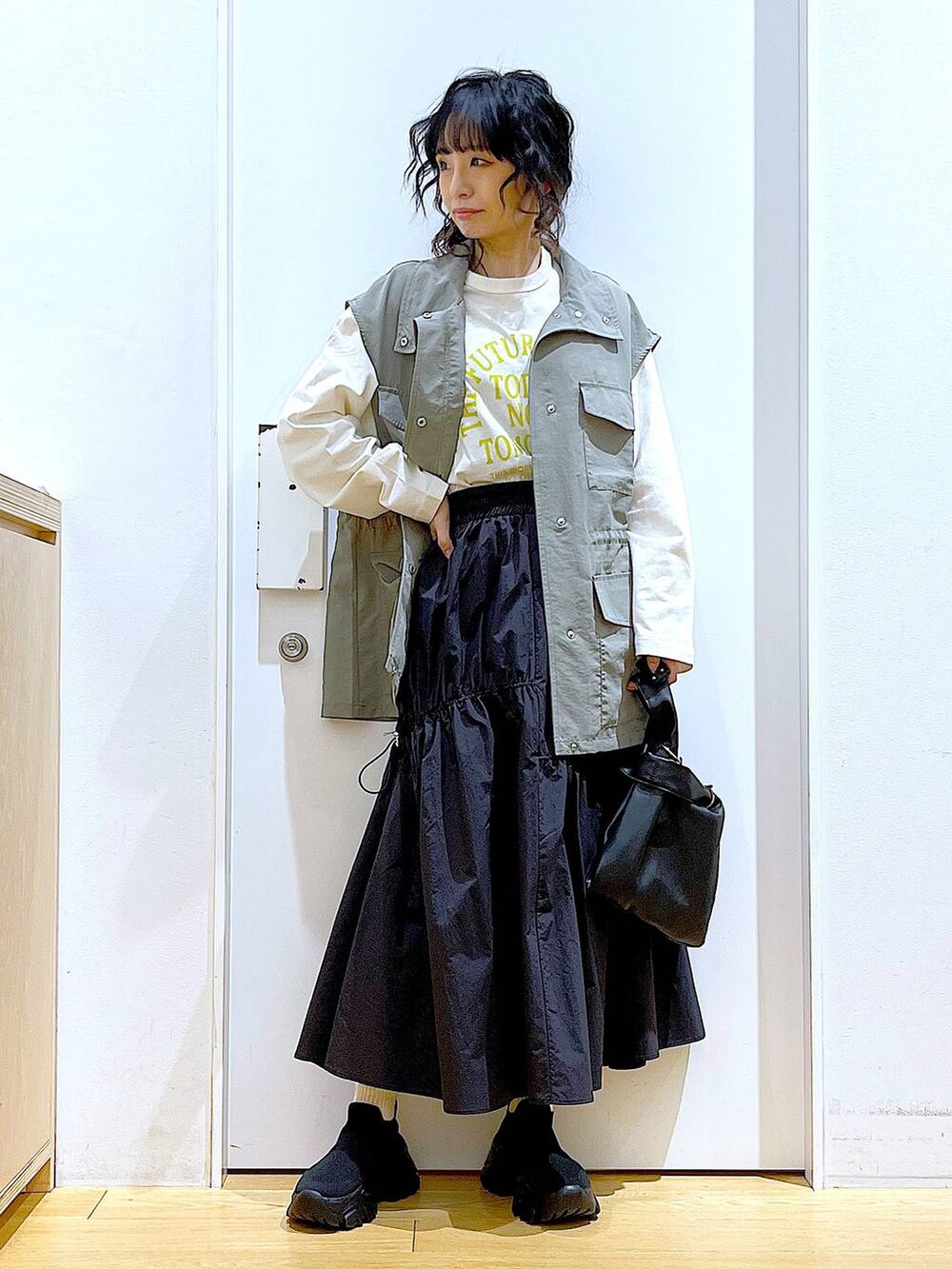 ブラック系のショルダーバッグ、ブラック系のスニーカー、ブラック系のスカートを着用したレディースの春コーディネートの2枚目の写真