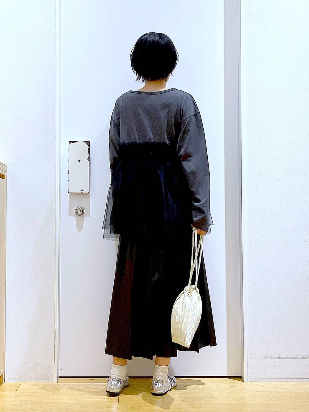 ホワイト系のショルダーバッグ、シルバー系のパンプス、ブラック系のスカートを着用したレディースの秋コーディネートの5枚目の写真