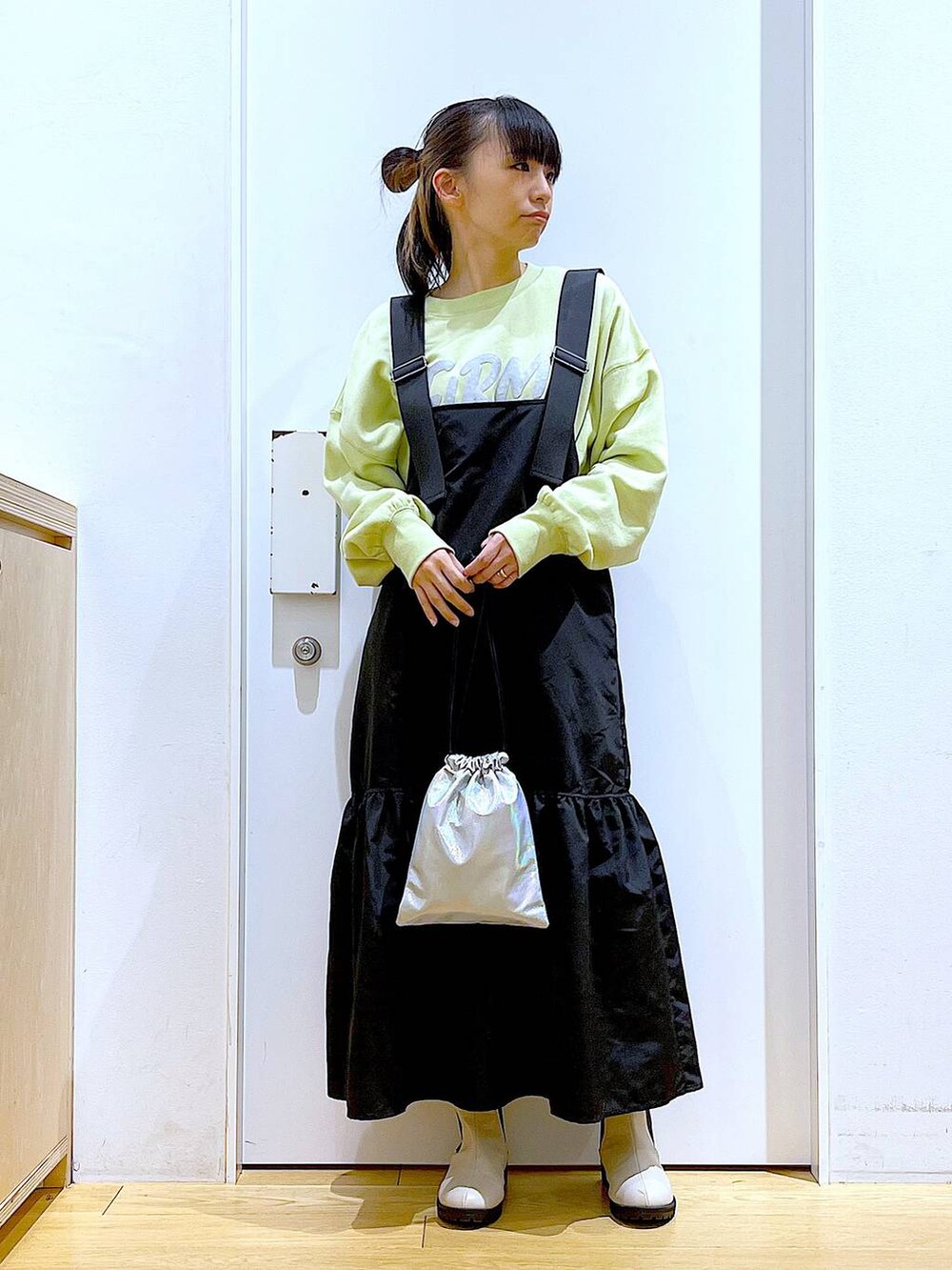 イエロー系のスウェット、ベージュ系のブーツ、その他のショルダーバッグを着用したレディースの冬コーディネートの2枚目の写真