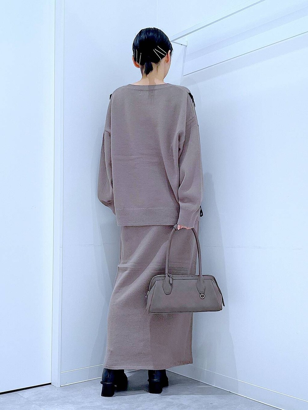 ブラウン系のニット/セーター、ブラウン系のスカート、ブラック系のブーツを着用したレディースの秋コーディネートの5枚目の写真