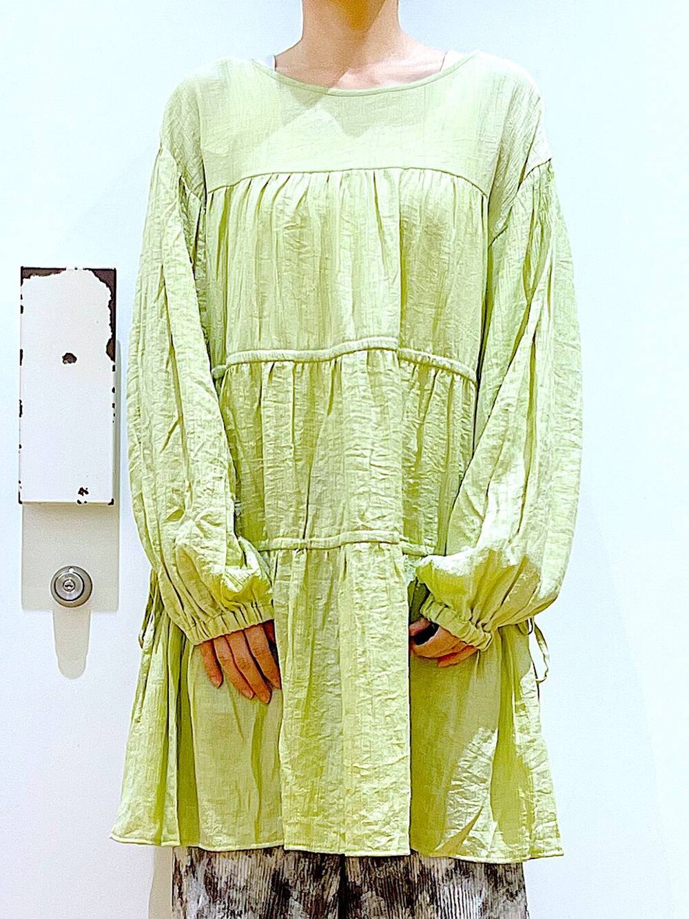 シルバー系のショルダーバッグ、シルバー系のパンプス、グリーン系のチュニックを着用したレディースの春コーディネートの7枚目の写真