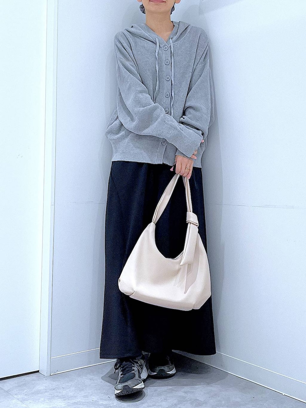 ホワイト系のショルダーバッグ、ブラック系のスカート、グレー系のカーディガン/ボレロを着用したレディースの春コーディネートの6枚目の写真