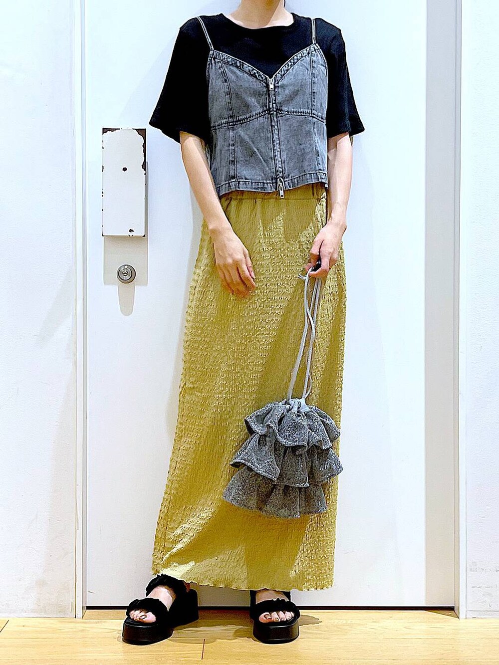 シルバー系のショルダーバッグ、グリーン系のスカート、ブラック系のTシャツ/カットソーを着用したレディースの夏コーディネートの6枚目の写真