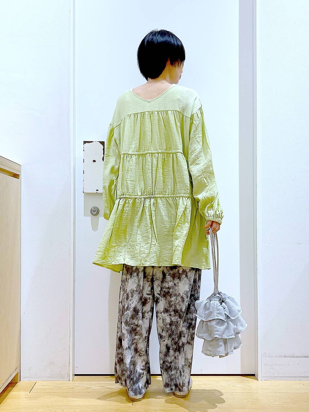 シルバー系のショルダーバッグ、シルバー系のパンプス、グリーン系のチュニックを着用したレディースの春コーディネートの5枚目の写真