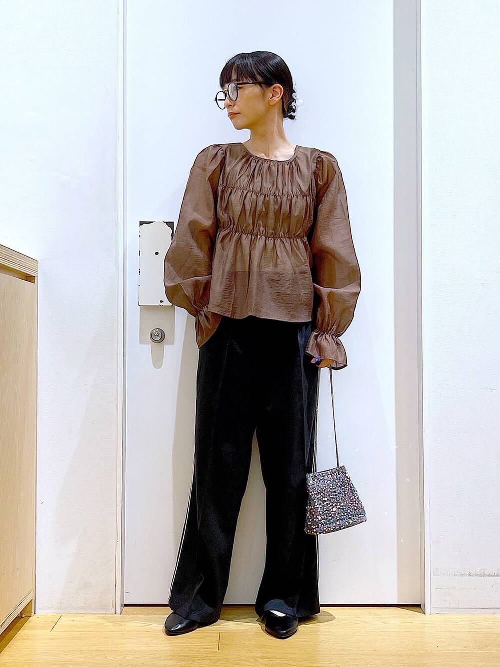 グレー系のショルダーバッグ、ブラック系のスラックス、ブラック系のパンプスを着用したレディースの秋コーディネートの2枚目の写真