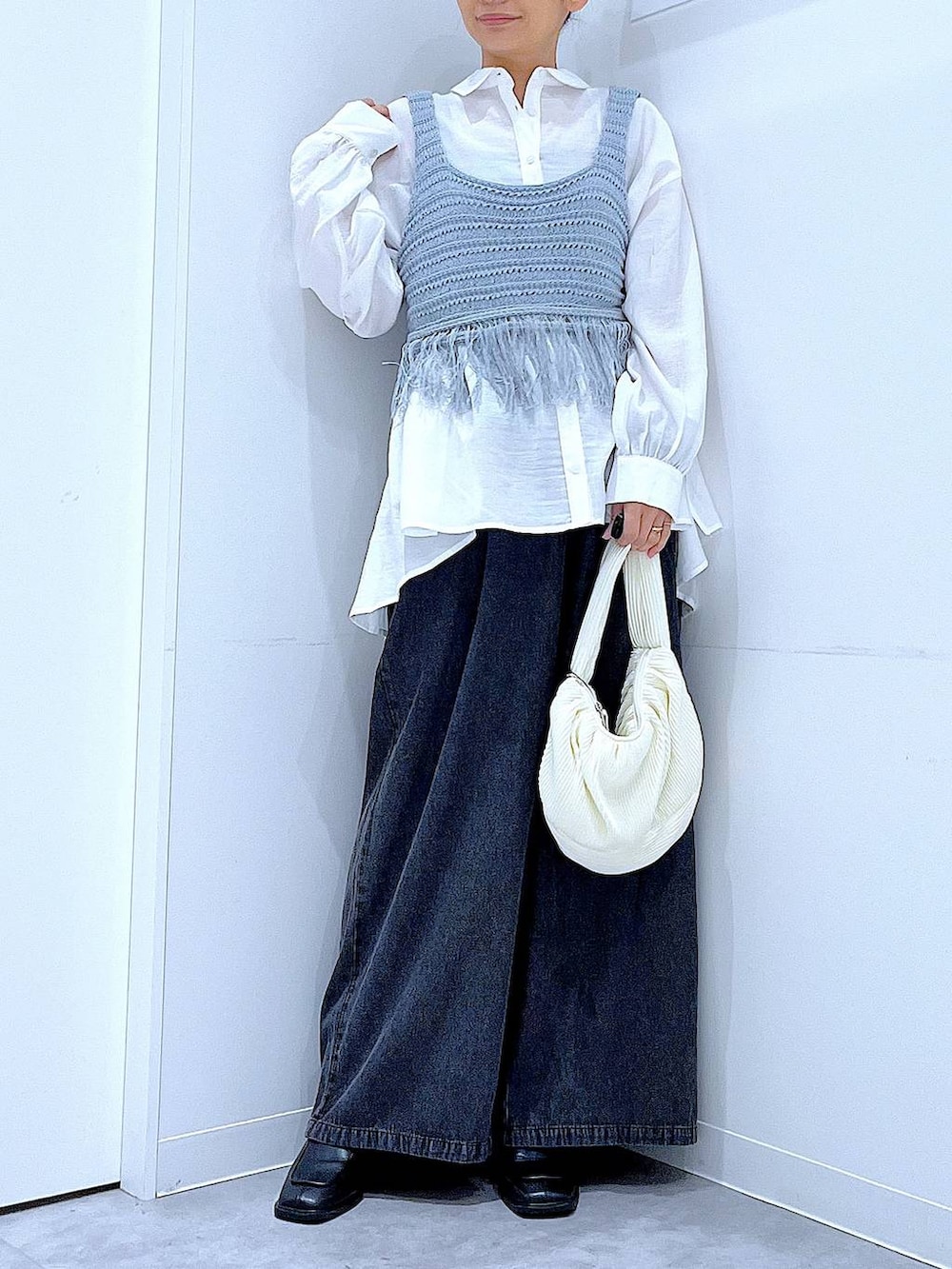 ブラック系のブーツ、ブルー系のベスト、ホワイト系のショルダーバッグを着用したレディースの春コーディネートの6枚目の写真