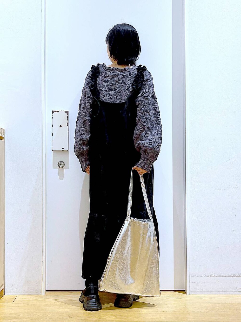 シルバー系のトートバッグ、ブラック系のブーツ、グレー系のニット/セーターを着用したレディースの冬コーディネートの5枚目の写真