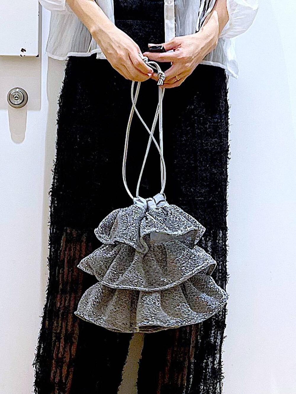 シルバー系のショルダーバッグ、ブラック系のニット/セーター、ブラック系のサンダルを着用したレディースの夏コーディネートの9枚目の写真