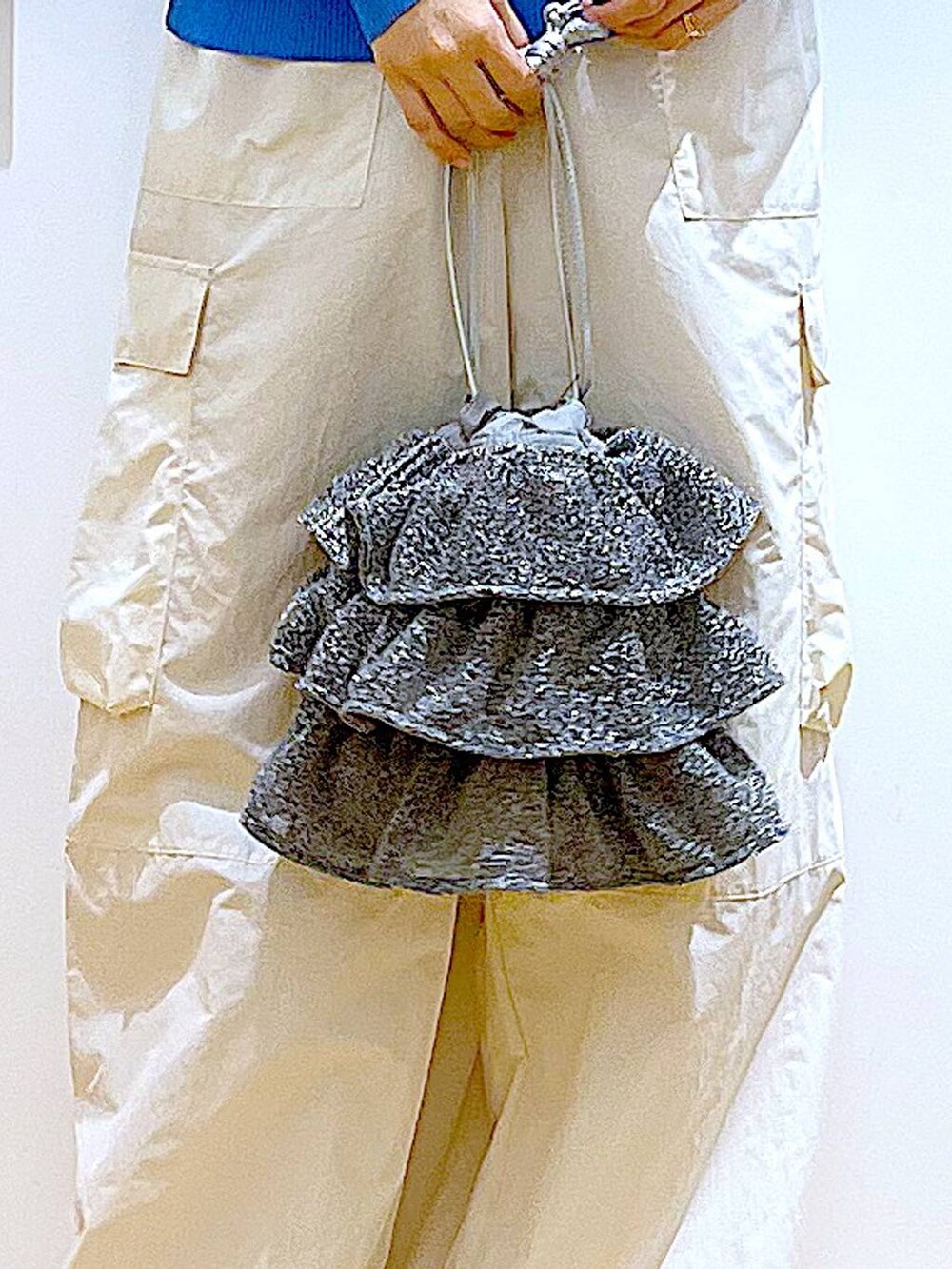 シルバー系のショルダーバッグ、ホワイト系のカーゴパンツ、ブラック系のニット/セーターを着用したレディースの夏コーディネートの9枚目の写真