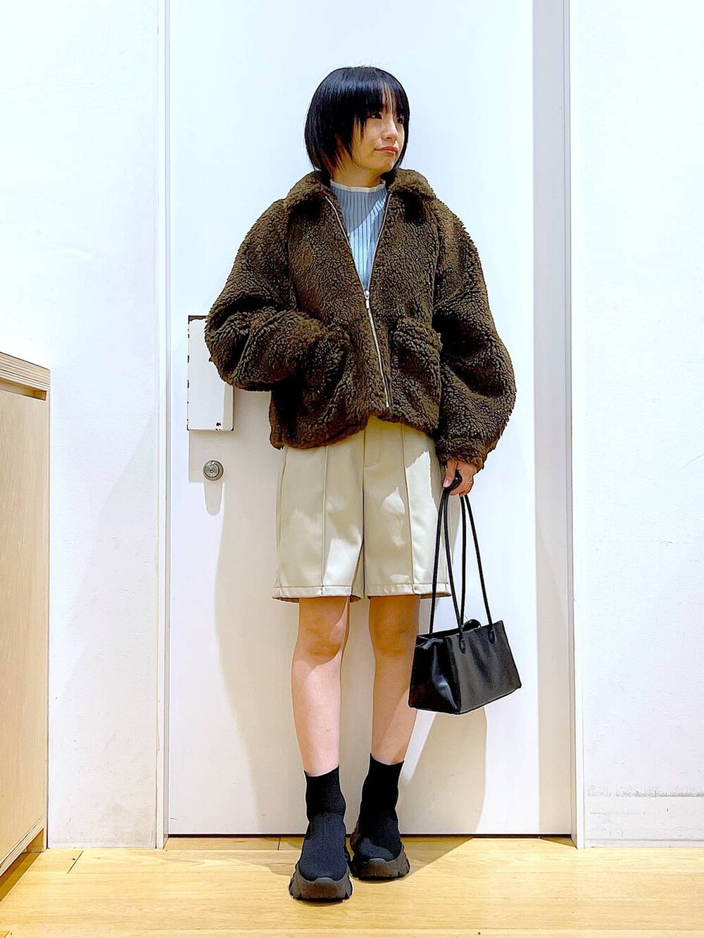 ブルー系のニット/セーター、ブラック系のトートバッグ、ブラック系のブーツを着用したレディースの冬コーディネートの2枚目の写真