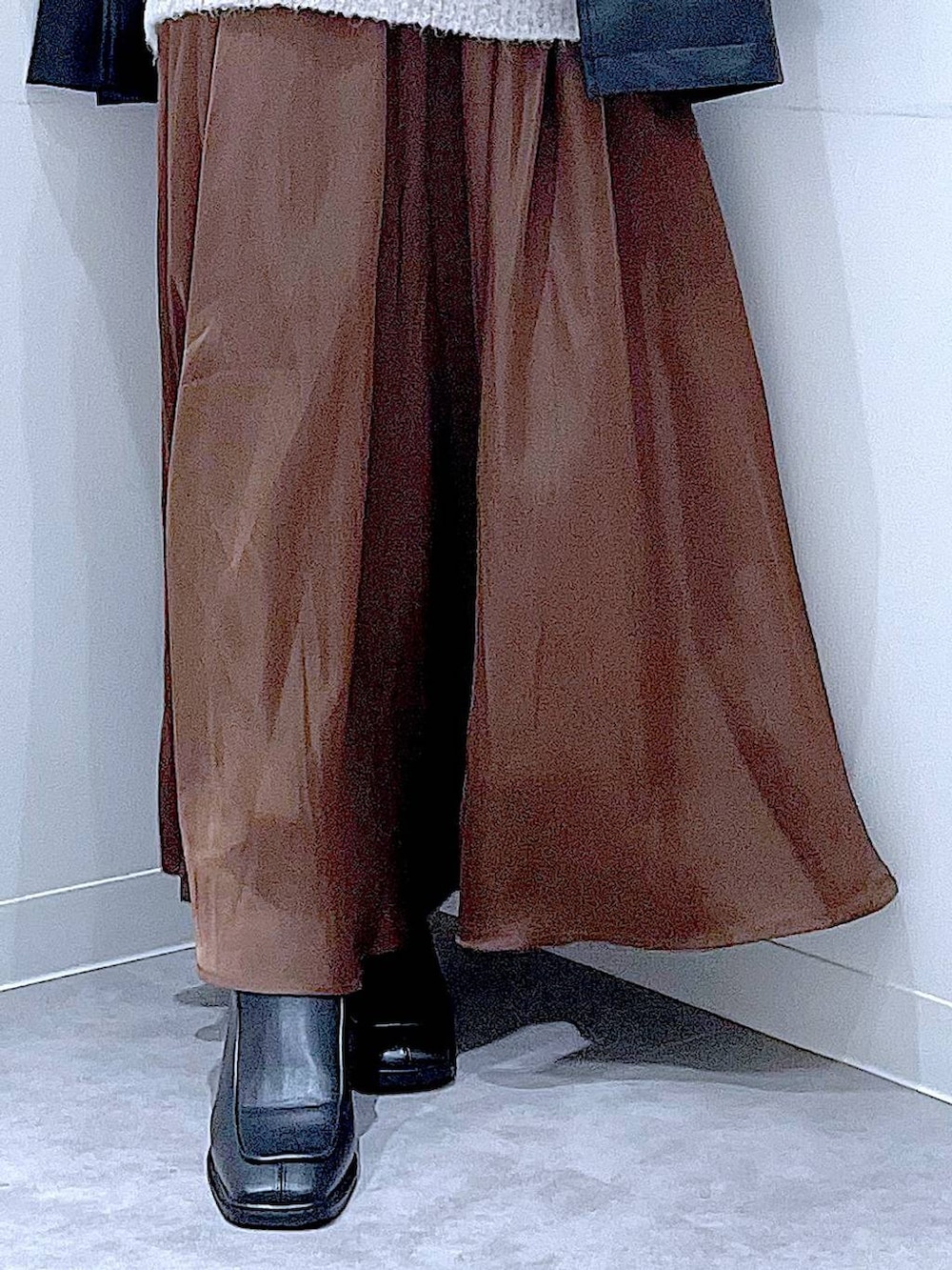 ブラック系のステンカラーコート、レッド系のニット/セーター、ブラック系のブーツを着用したレディースの冬コーディネートの8枚目の写真