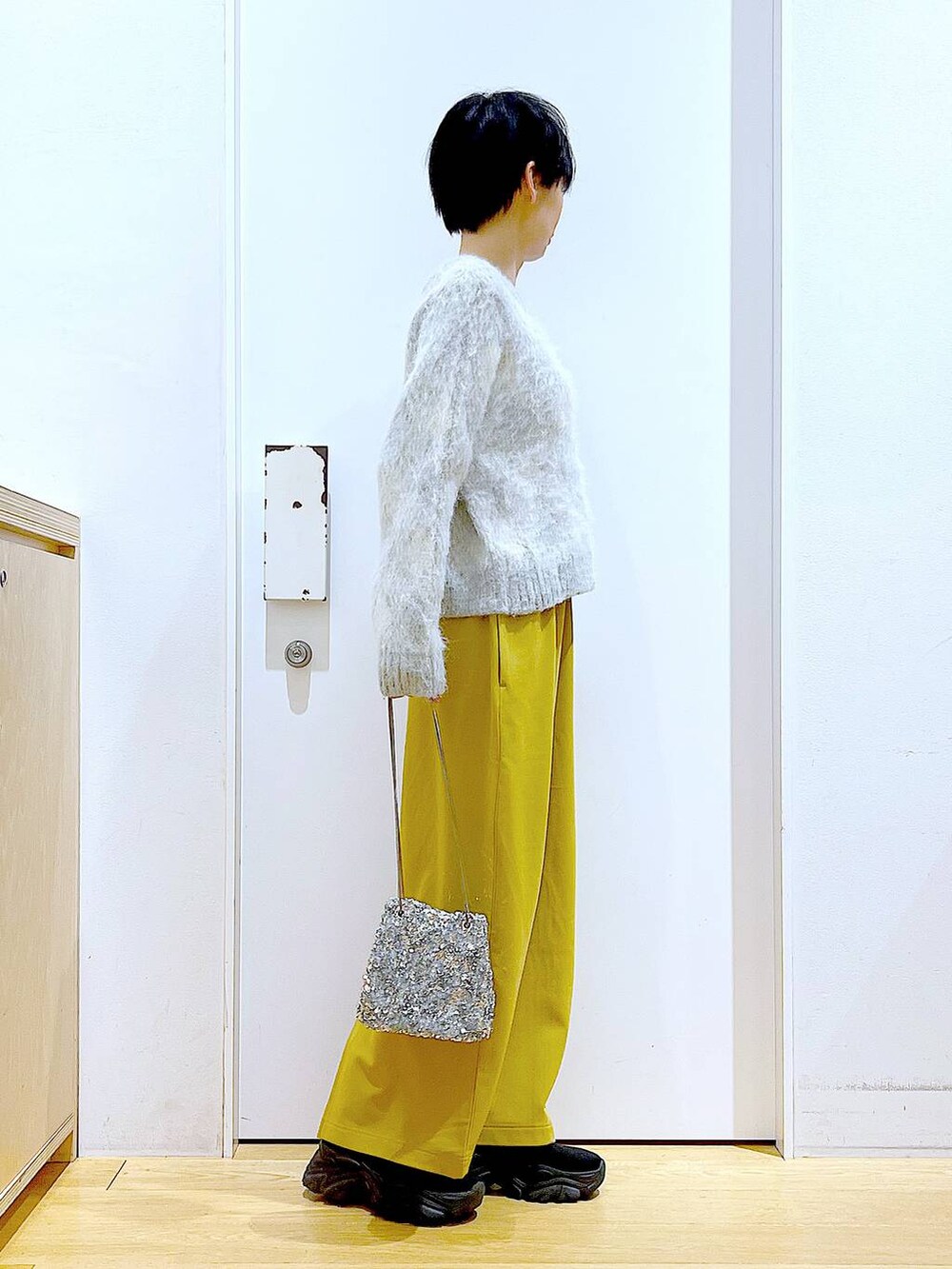 ブラック系のブーツ、イエロー系のスカート、その他のショルダーバッグを着用したレディースの冬コーディネートの4枚目の写真