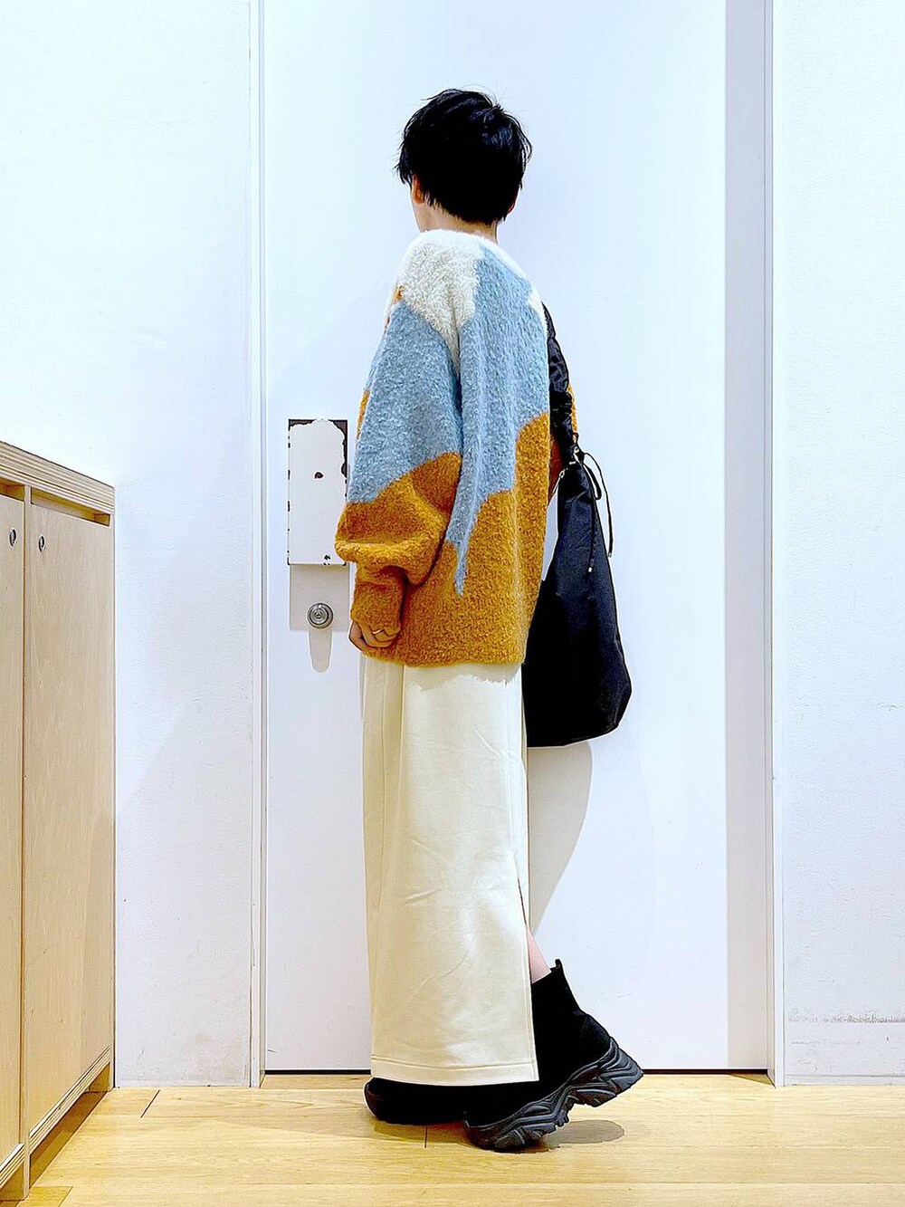 ブラック系のショルダーバッグ、ブラック系のブーツ、オレンジ系のニット/セーターを着用したレディースの冬コーディネートの3枚目の写真