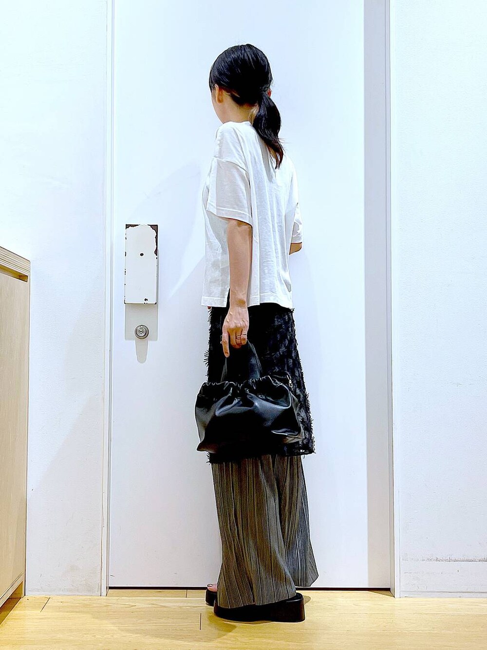 ブラック系のサンダル、ブラック系のショルダーバッグ、ブラック系のスカートを着用したレディースの秋コーディネートの3枚目の写真