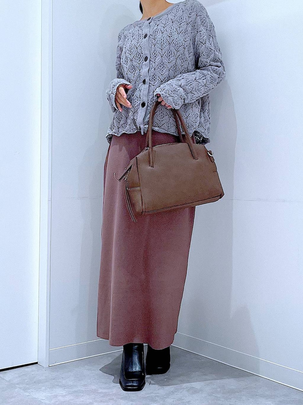 ブラウン系のボストンバッグ、ブラック系のブーツ、グレー系のカーディガン/ボレロを着用したレディースの冬コーディネートの6枚目の写真