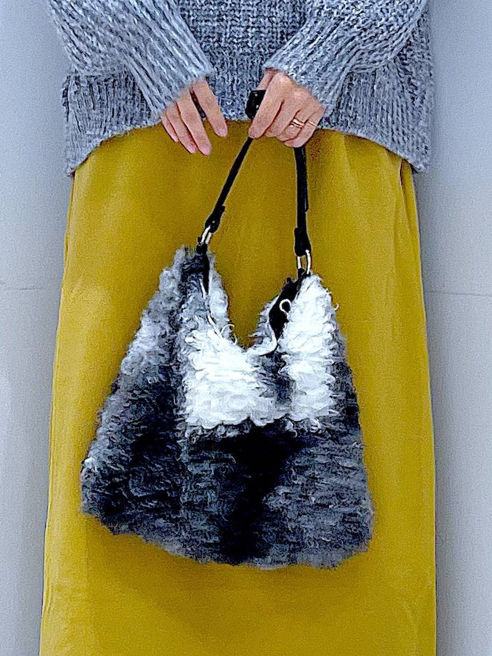 グレー系のニット/セーター、イエロー系のスカート、ブラック系のブーツを着用したレディースの冬コーディネートの9枚目の写真