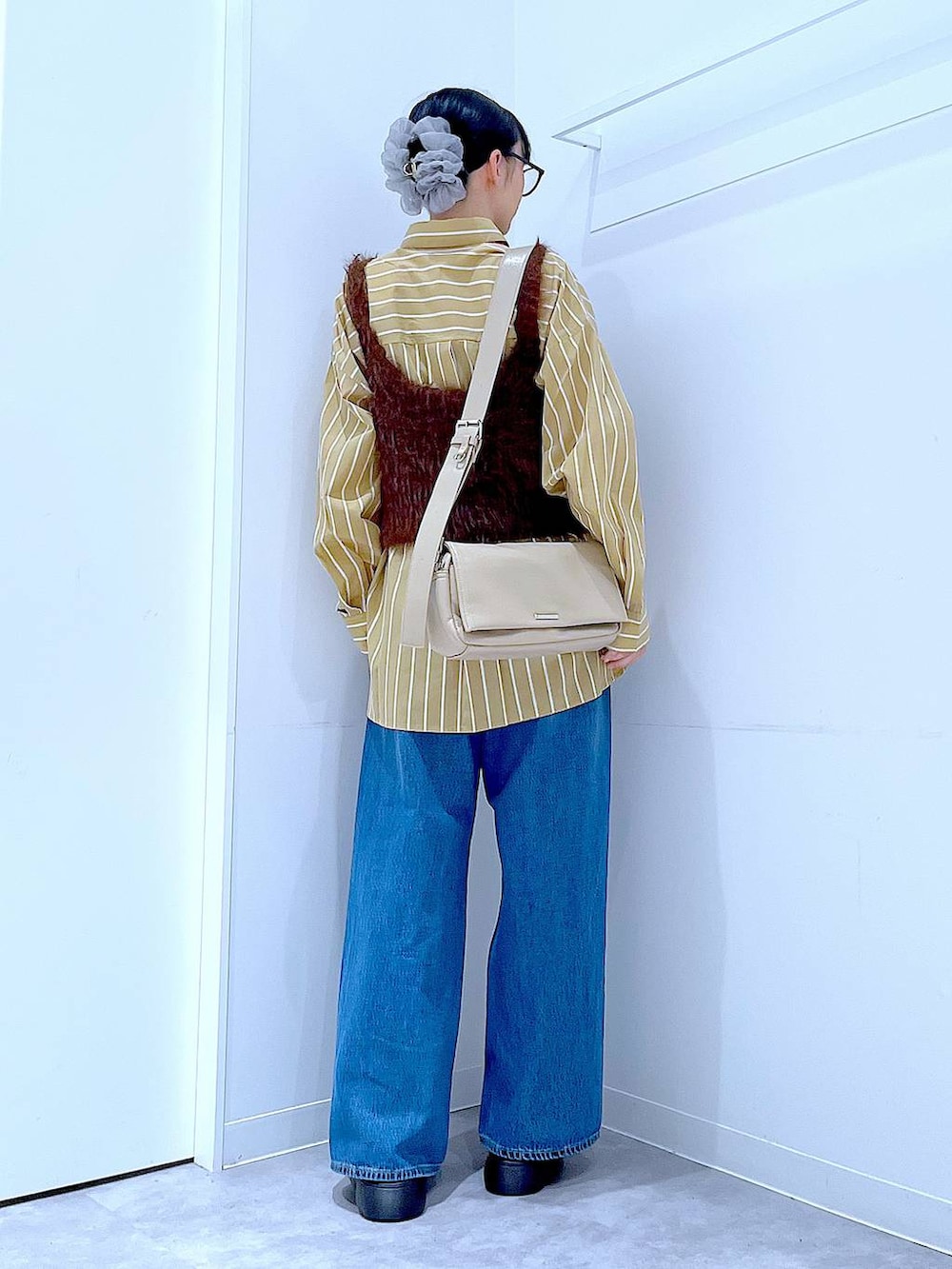 ブルー系のデニムパンツ、イエロー系のシャツ/ブラウス、ブラウン系のベストを着用したレディースの秋コーディネートの5枚目の写真
