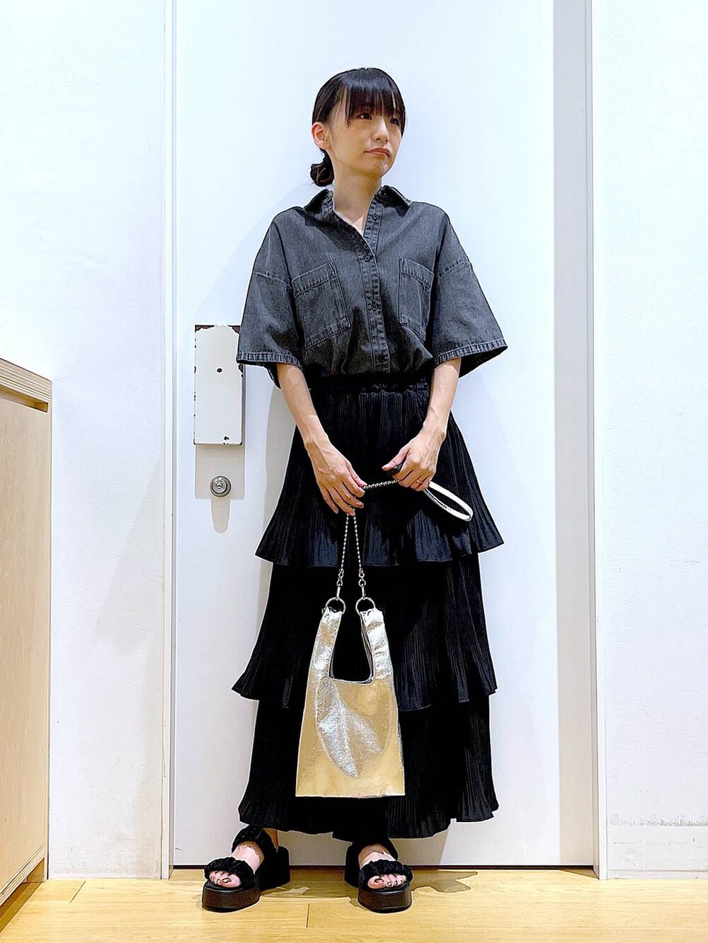 シルバー系のショルダーバッグ、ブラック系のスカート、ブラック系のサンダルを着用したレディースの夏コーディネートの2枚目の写真