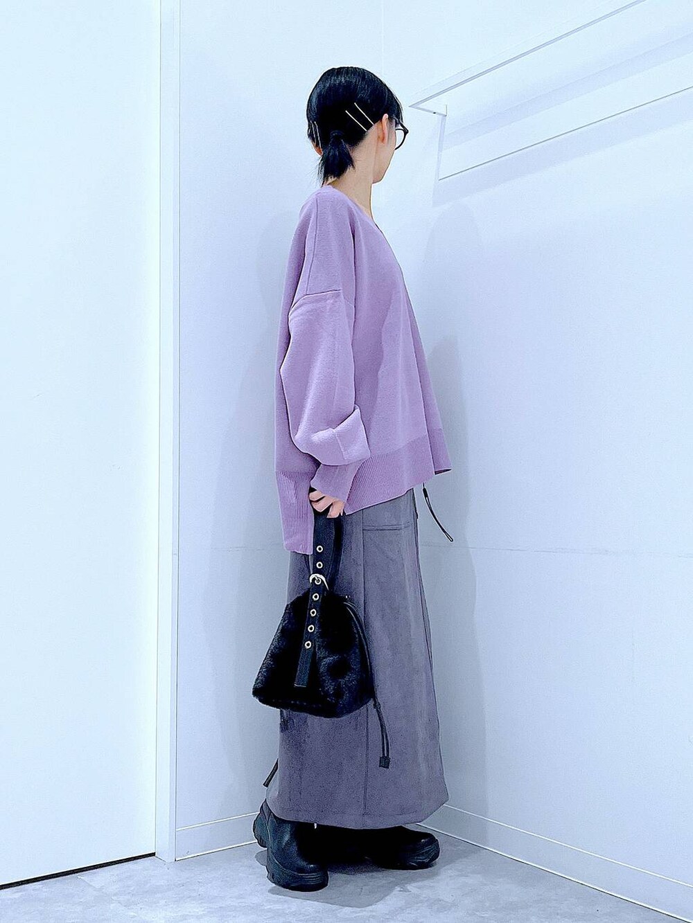 ブラック系のハンドバッグ、ブラック系のブーツ、グレー系のスカートを着用したレディースの冬コーディネートの4枚目の写真