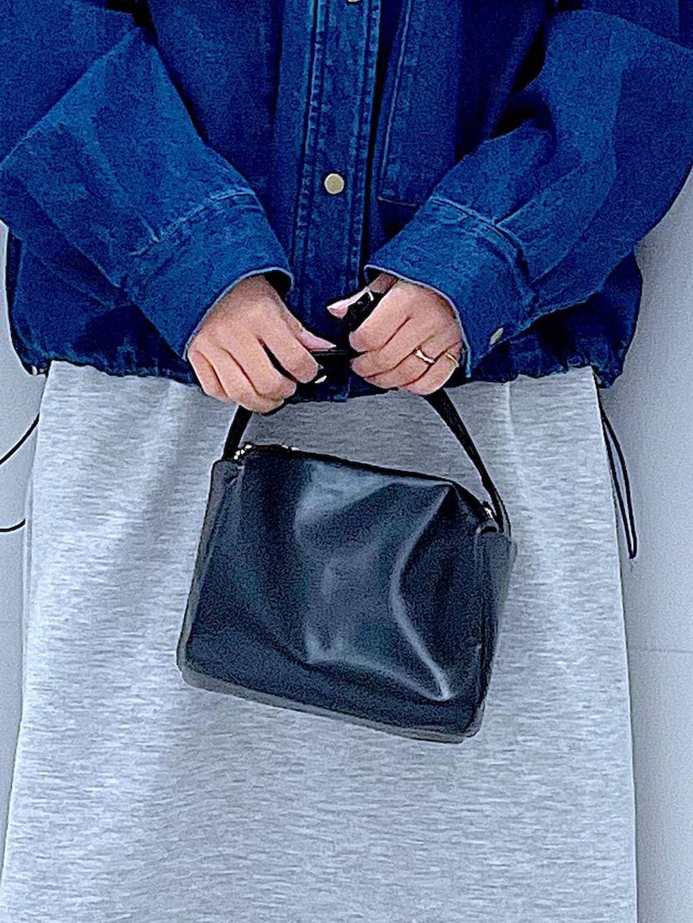 ブラック系のショルダーバッグ、グレー系のスカート、ブラック系のサンダルを着用したレディースの春コーディネートの9枚目の写真