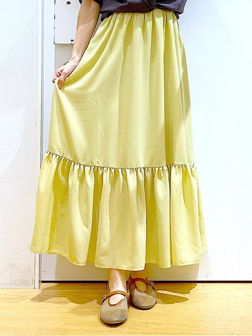 ブラック系のショルダーバッグ、ベージュ系のパンプス、イエロー系のワンピースを着用したレディースの春コーディネートの8枚目の写真